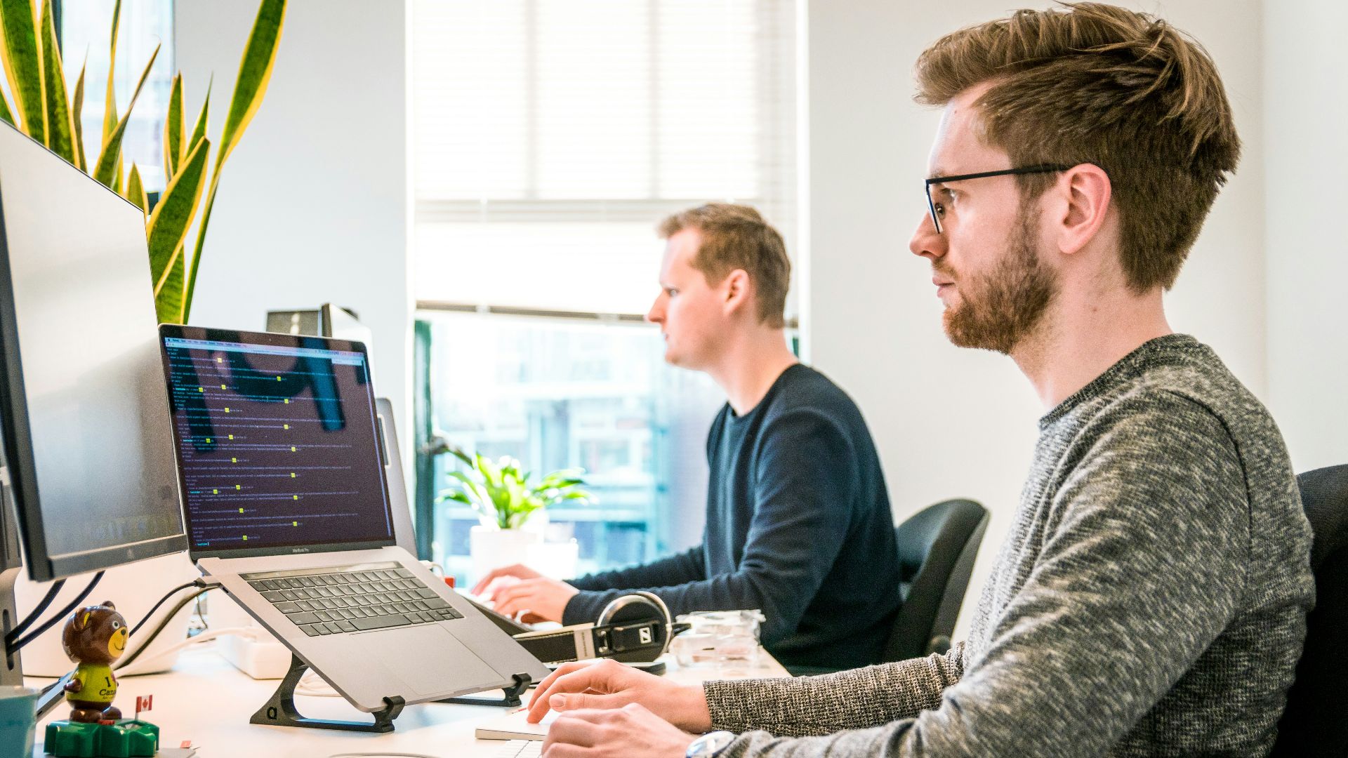 man sitting on chair wearing gray crew-neck long-sleeved shirt using Apple Magic Keyboard