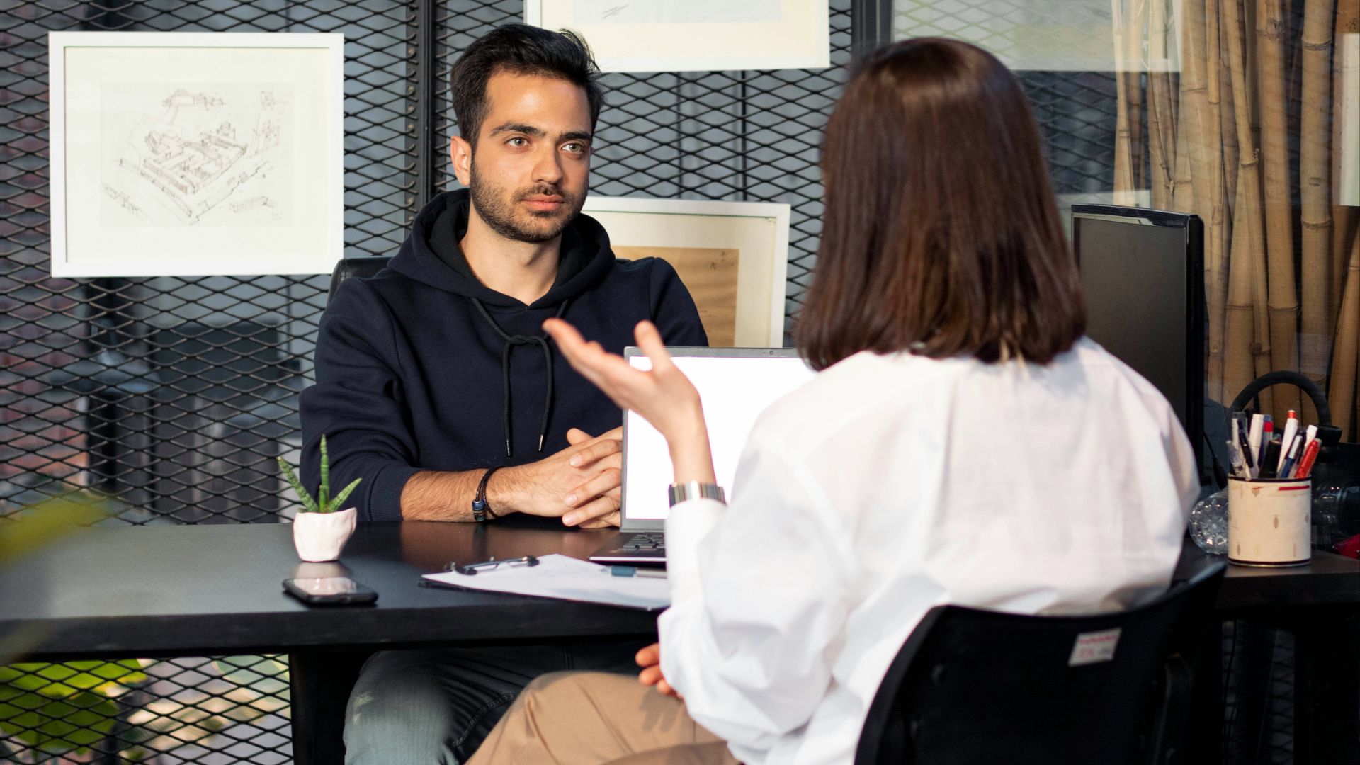 a man sitting at a desk talking to a woman
