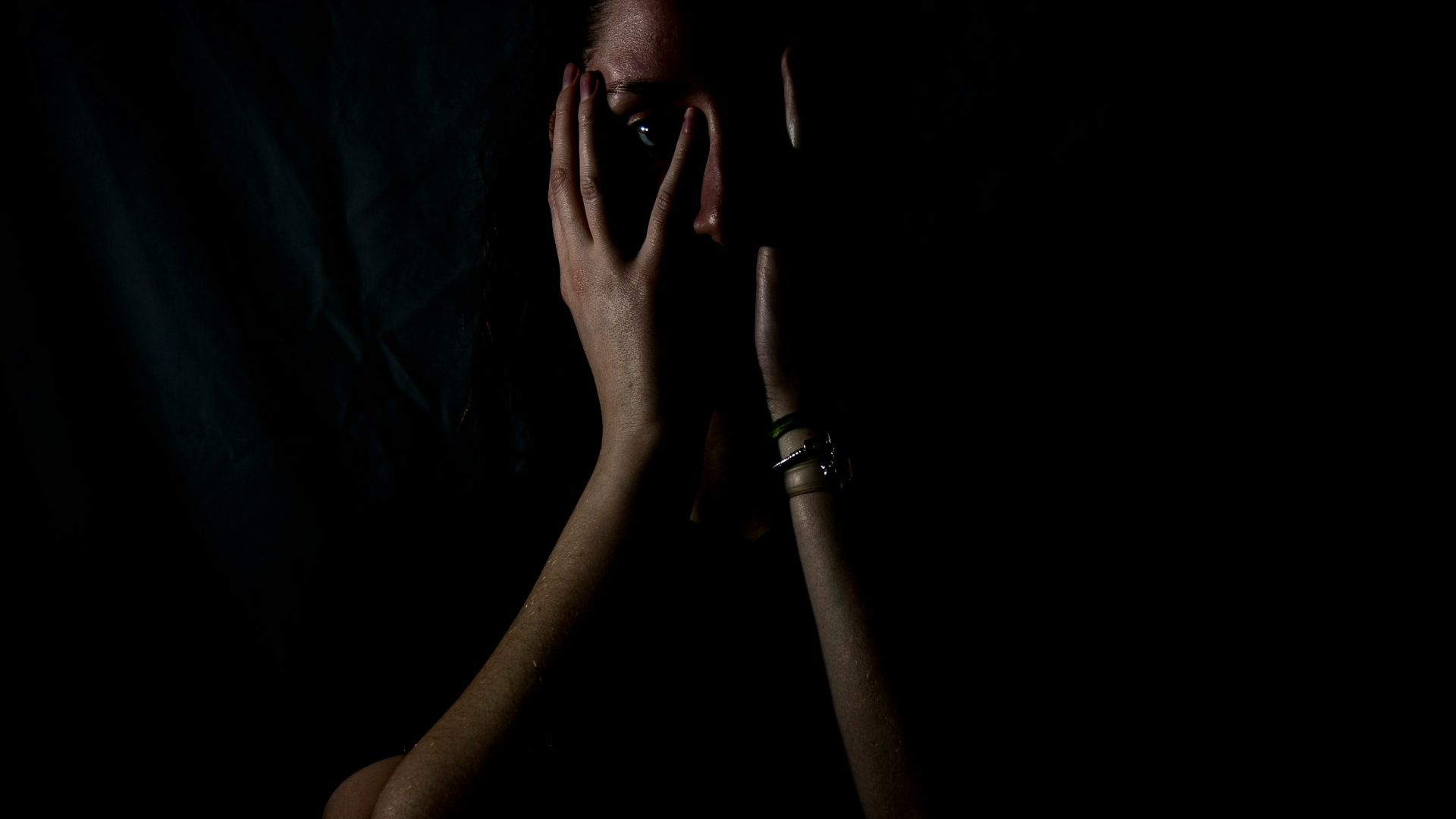 woman holding her face in dark room