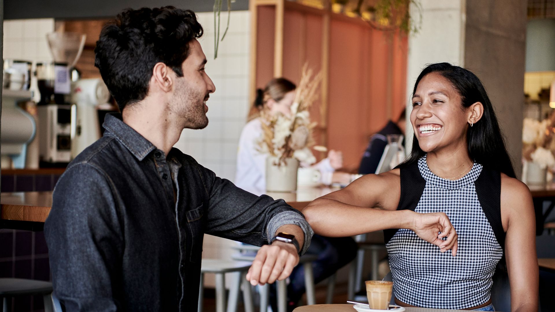 man in black shirt elbow bumping with woman in a restaurant