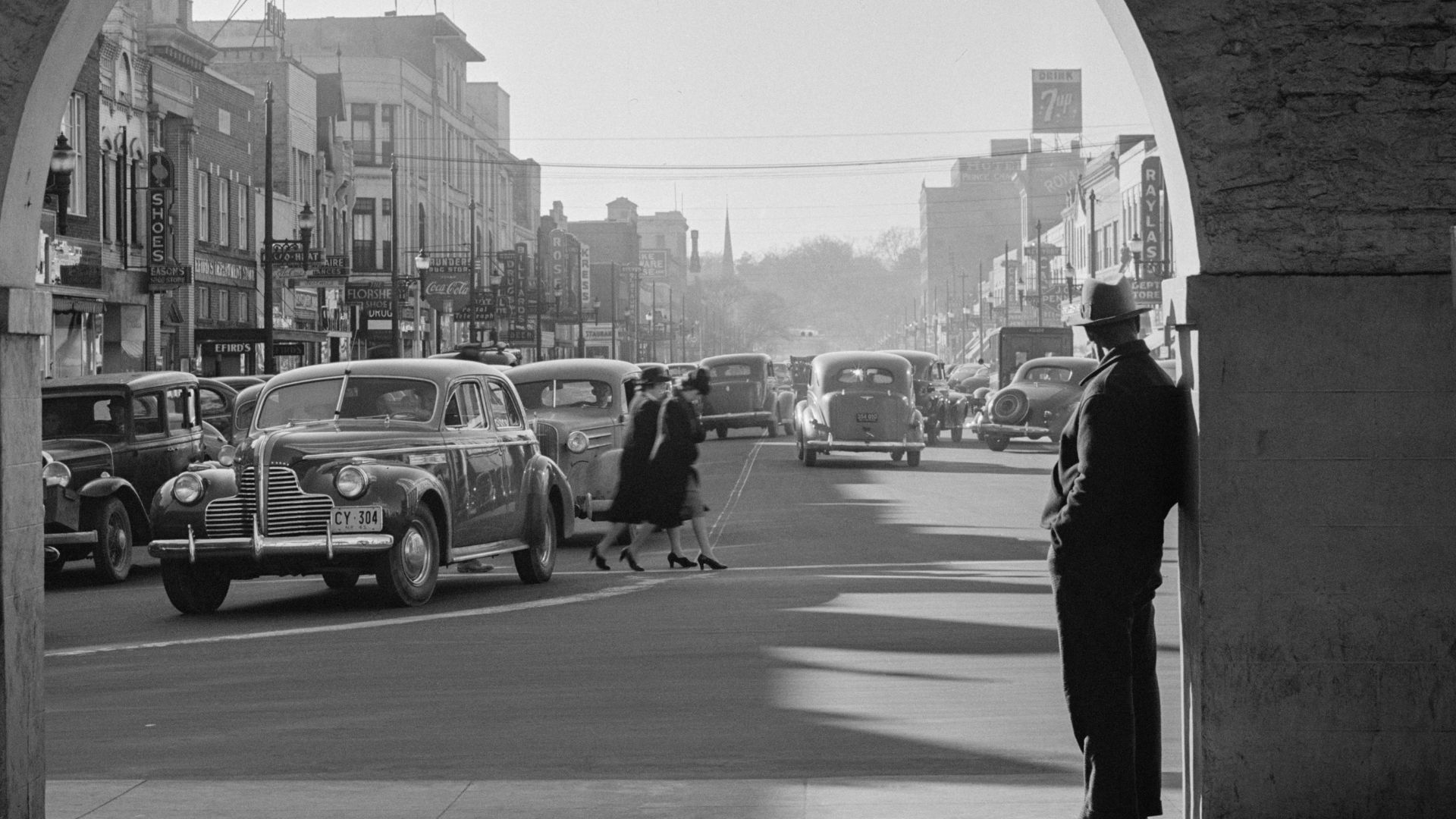a black and white photo of a man standing in the middle of a street