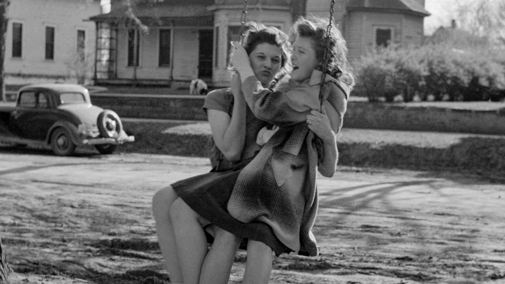 a black and white photo of a woman sitting on a swing