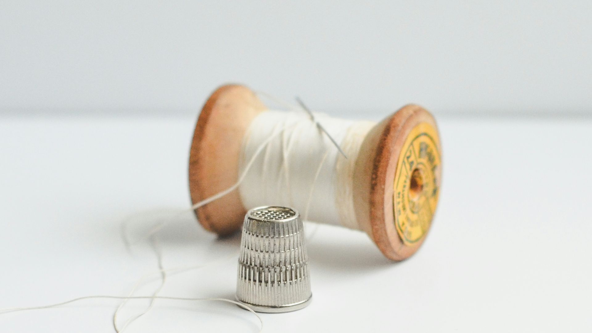 A spool of thread, needle, and thimble.