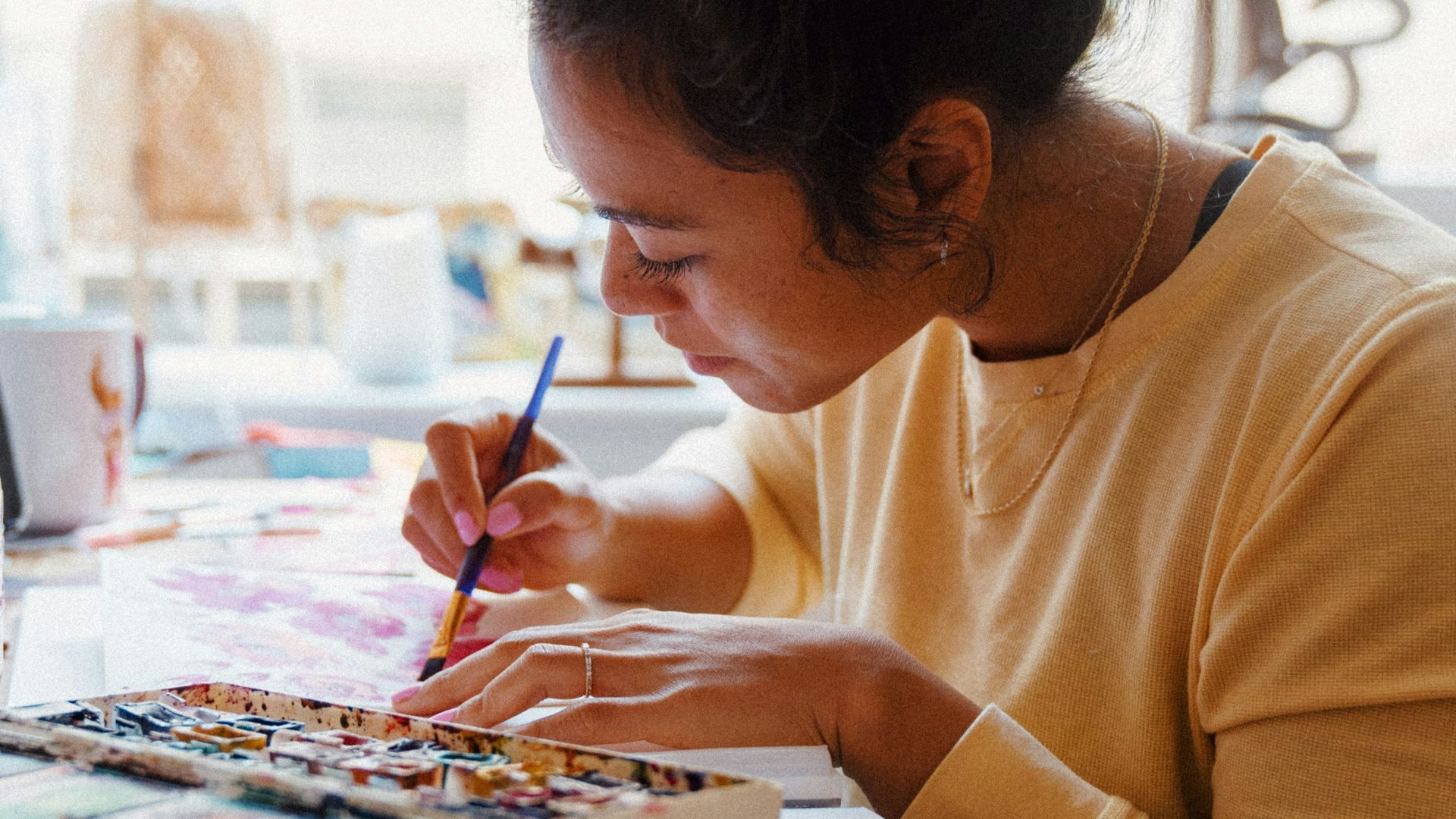 woman in yellow crew neck long sleeve shirt writing on white paper