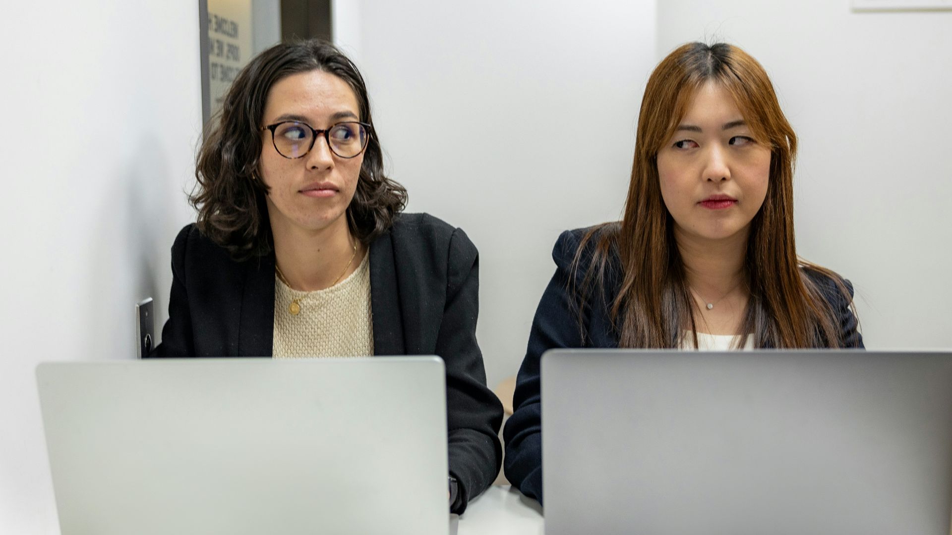 two women sitting at a table with laptops