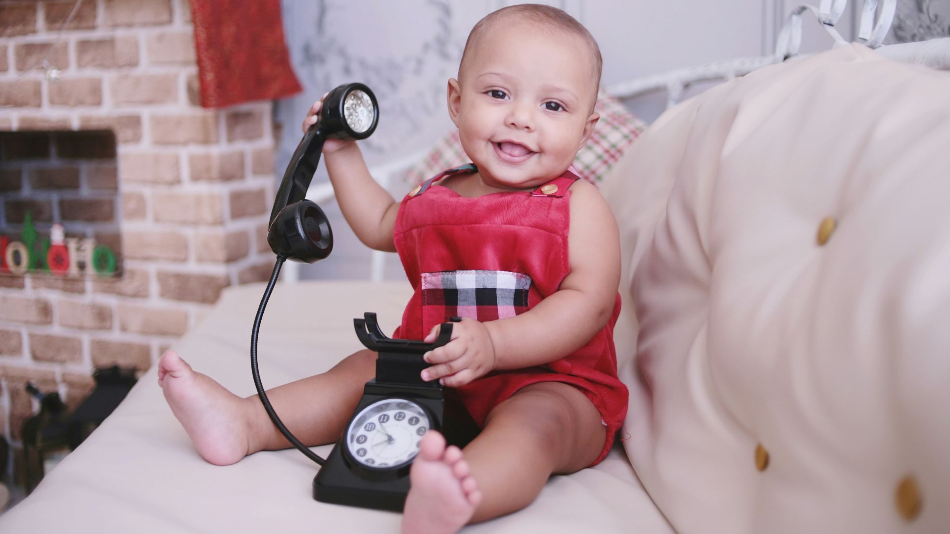baby in red shirt sitting on white textile