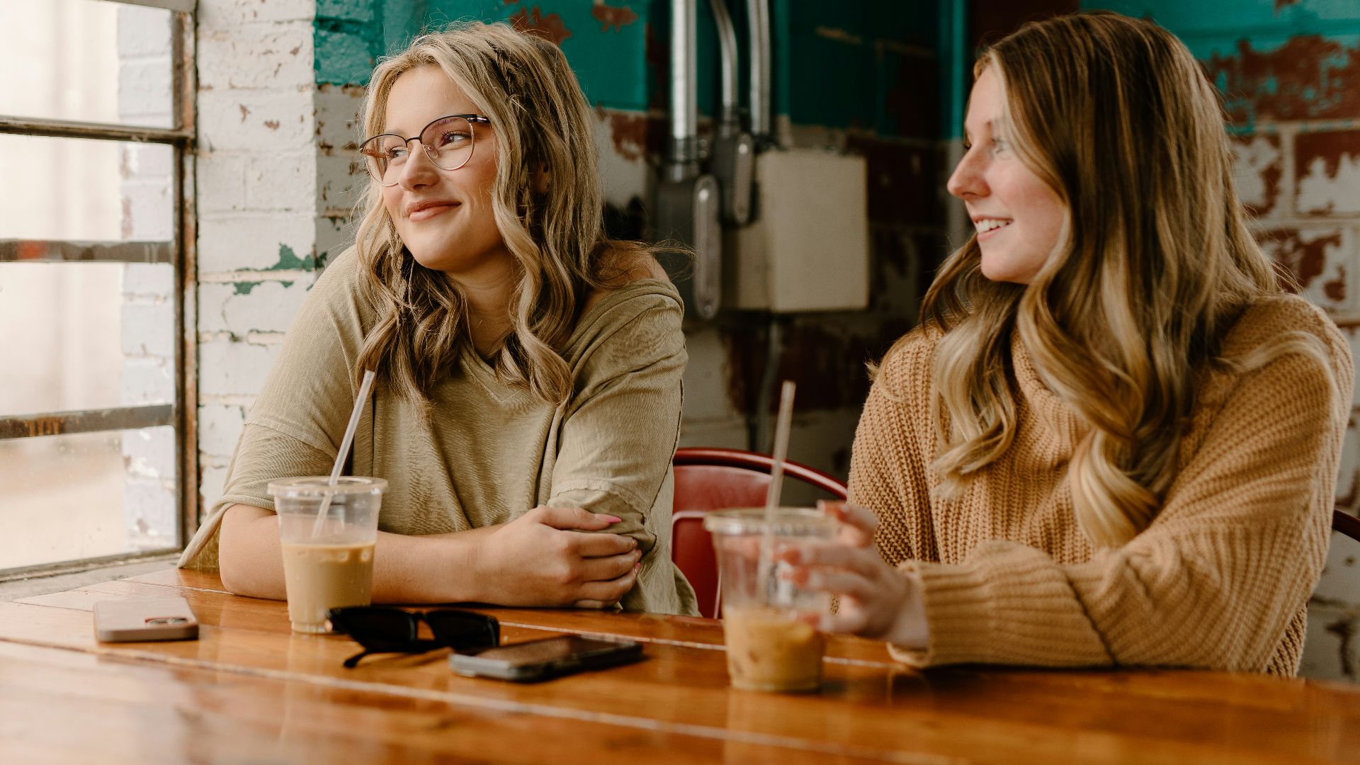 two women sitting at a table with drinks