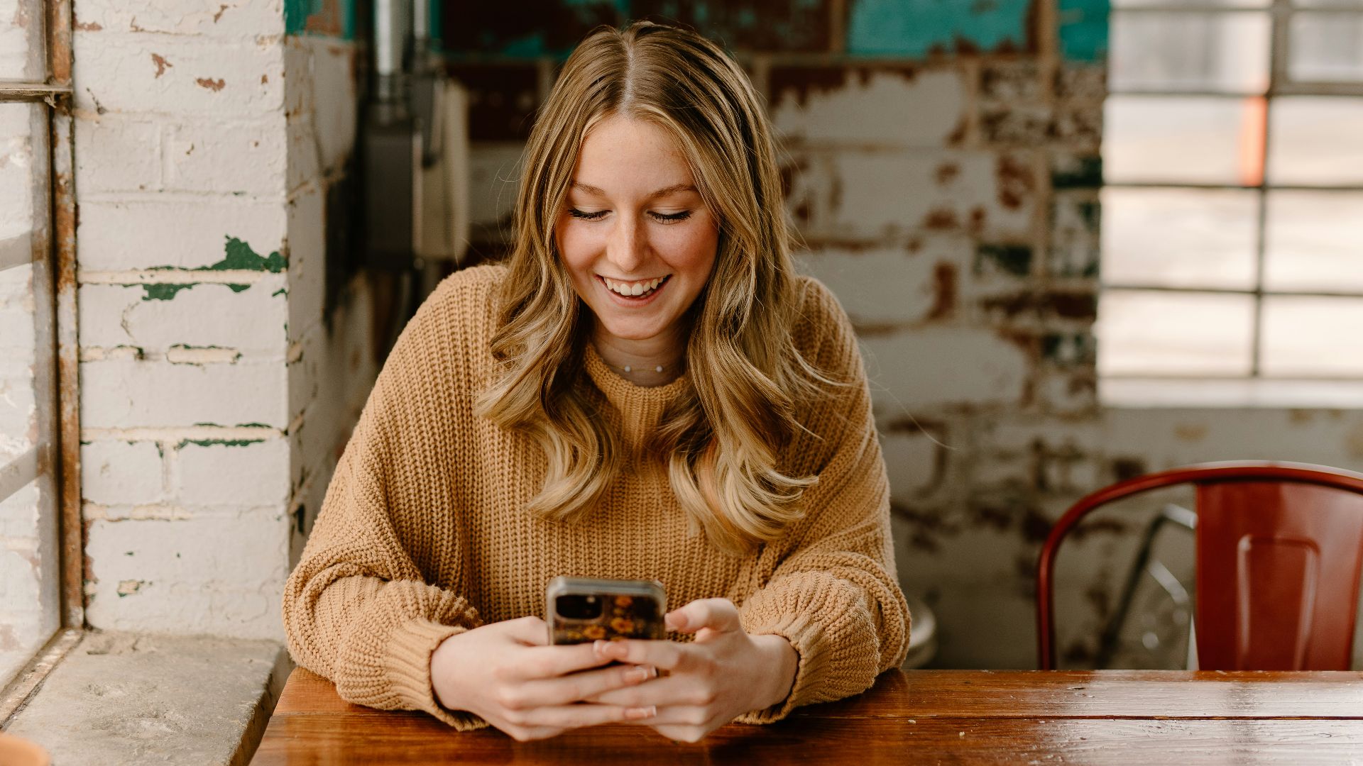 a woman sitting at a table looking at her cell phone