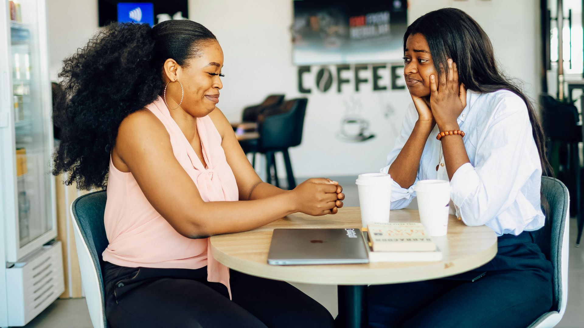 A couple of women sitting at a table with a laptop