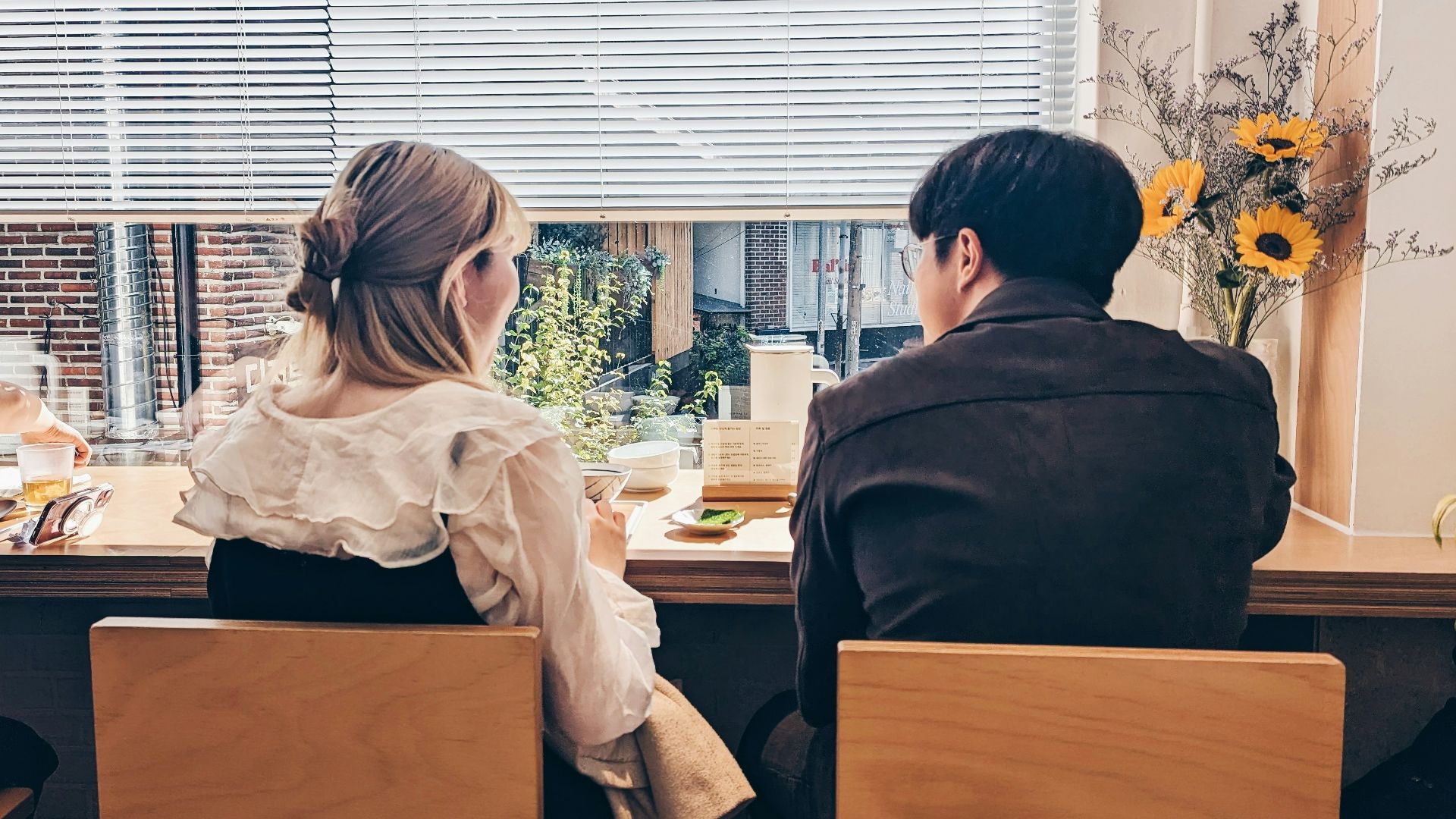 a man and a woman sitting at a table in front of a window