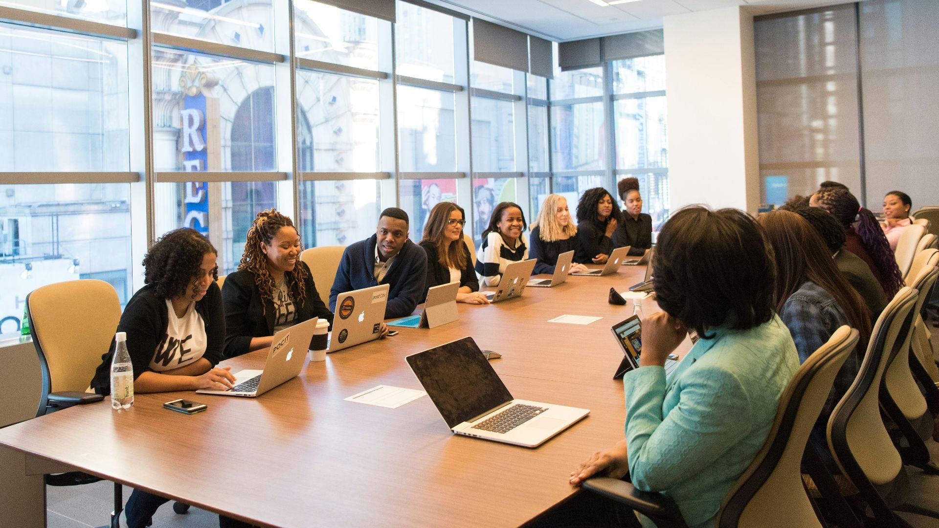 group of people sitting beside rectangular wooden table with laptops