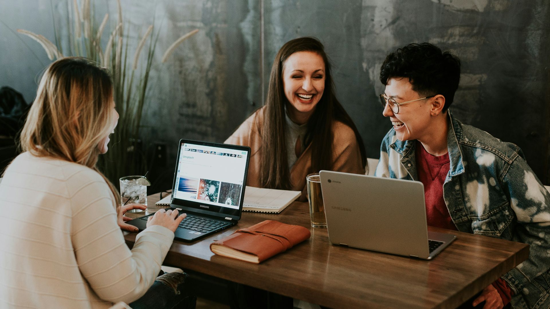 three people sitting in front of table laughing together
