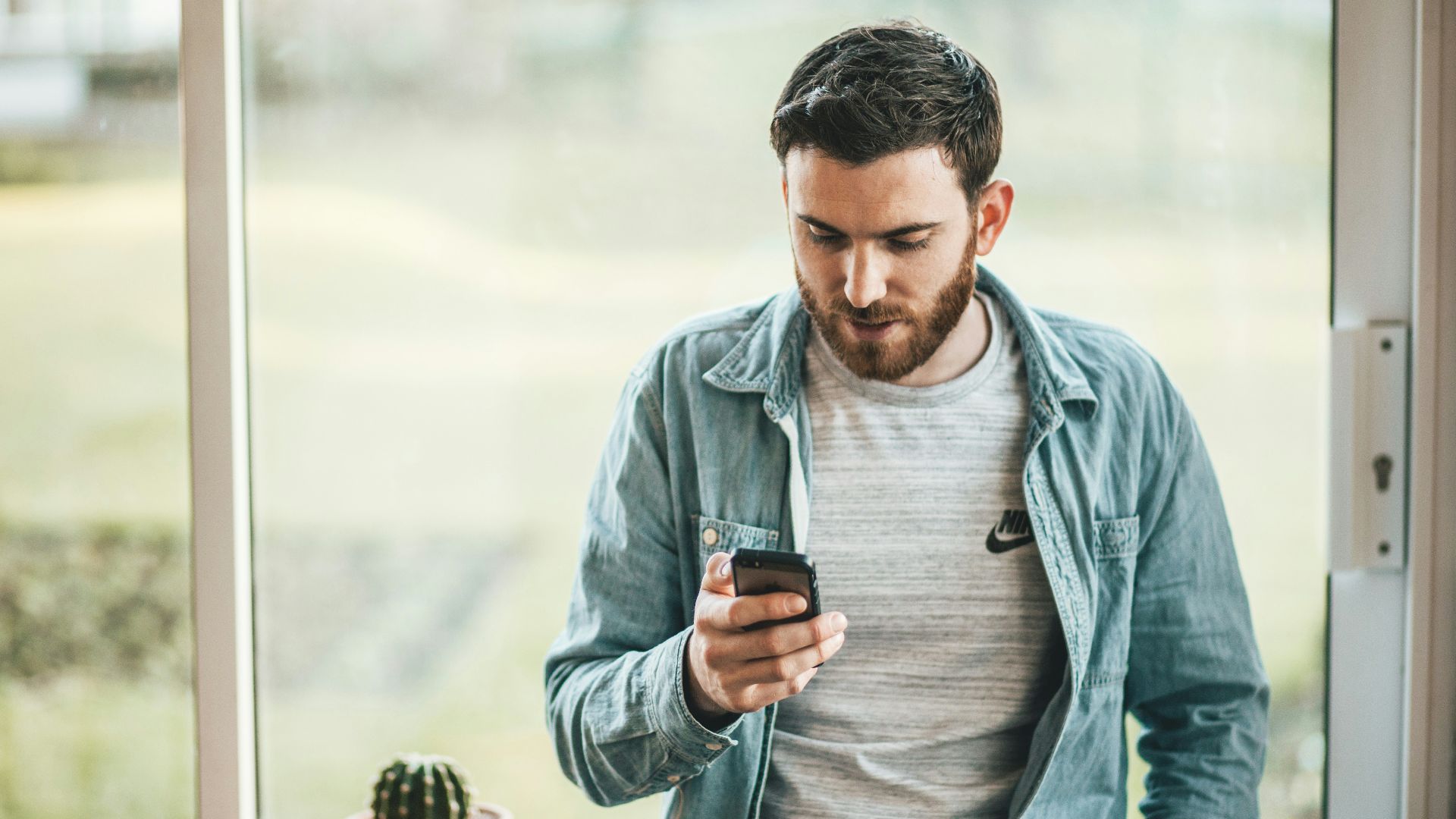 man holding a smartphone near the window