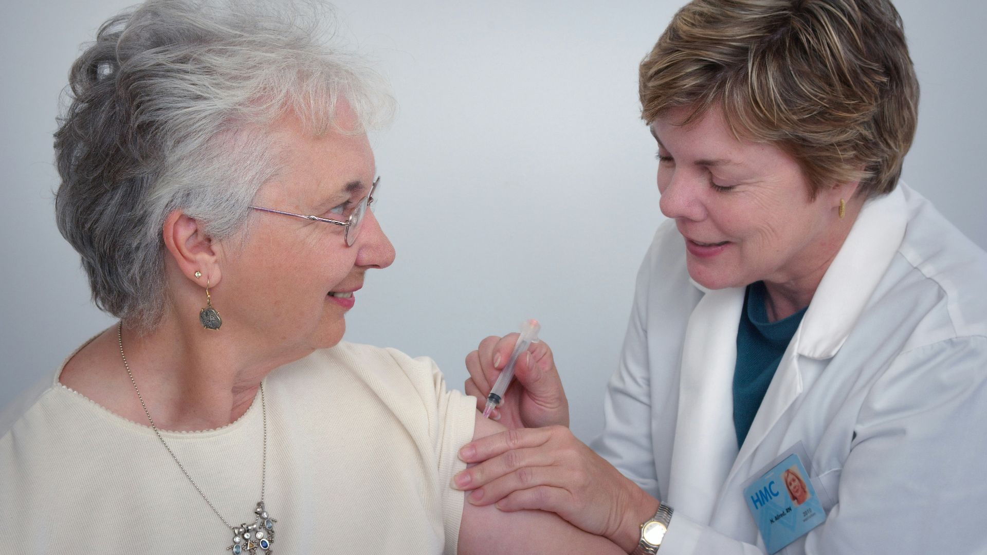 woman inject a woman on left shoulder