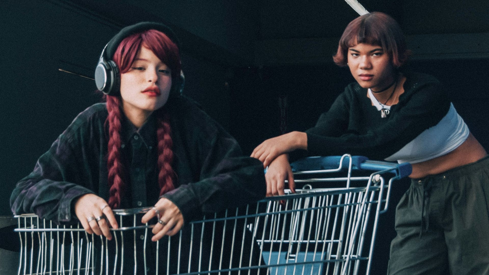 a couple of women standing next to a shopping cart