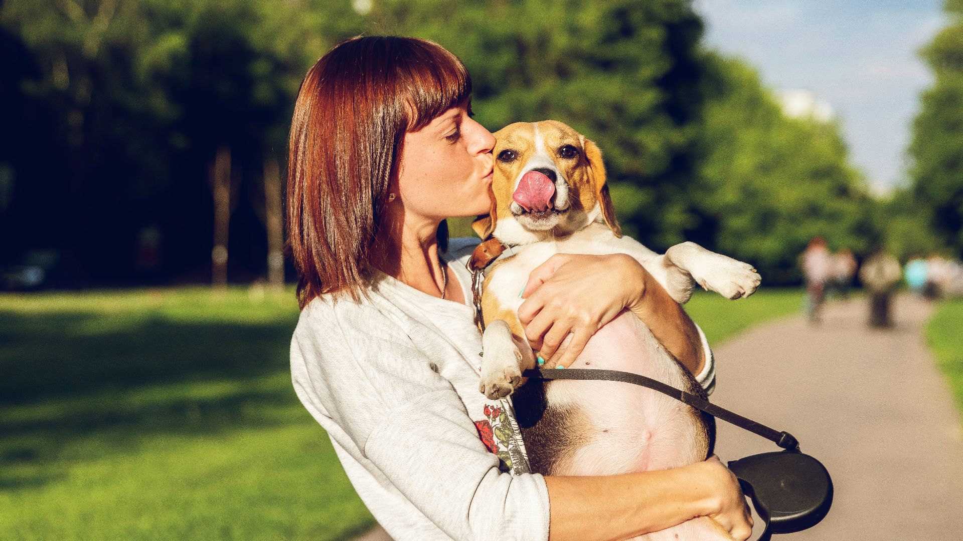 woman carrying and kissing dog