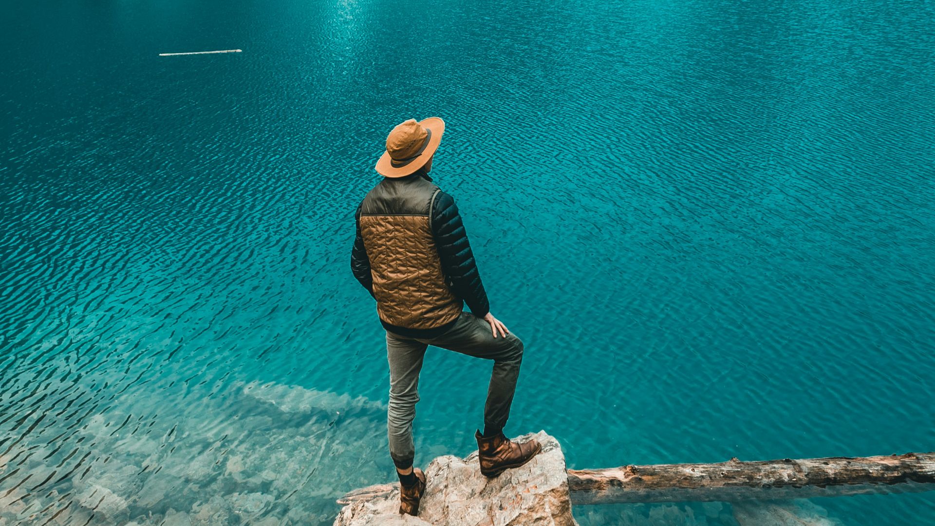 man standing on rock near lake