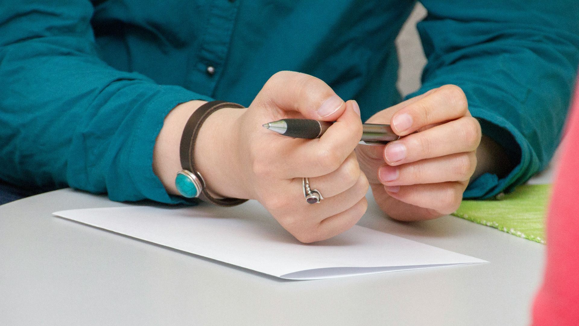 a person sitting at a table writing on a piece of paper