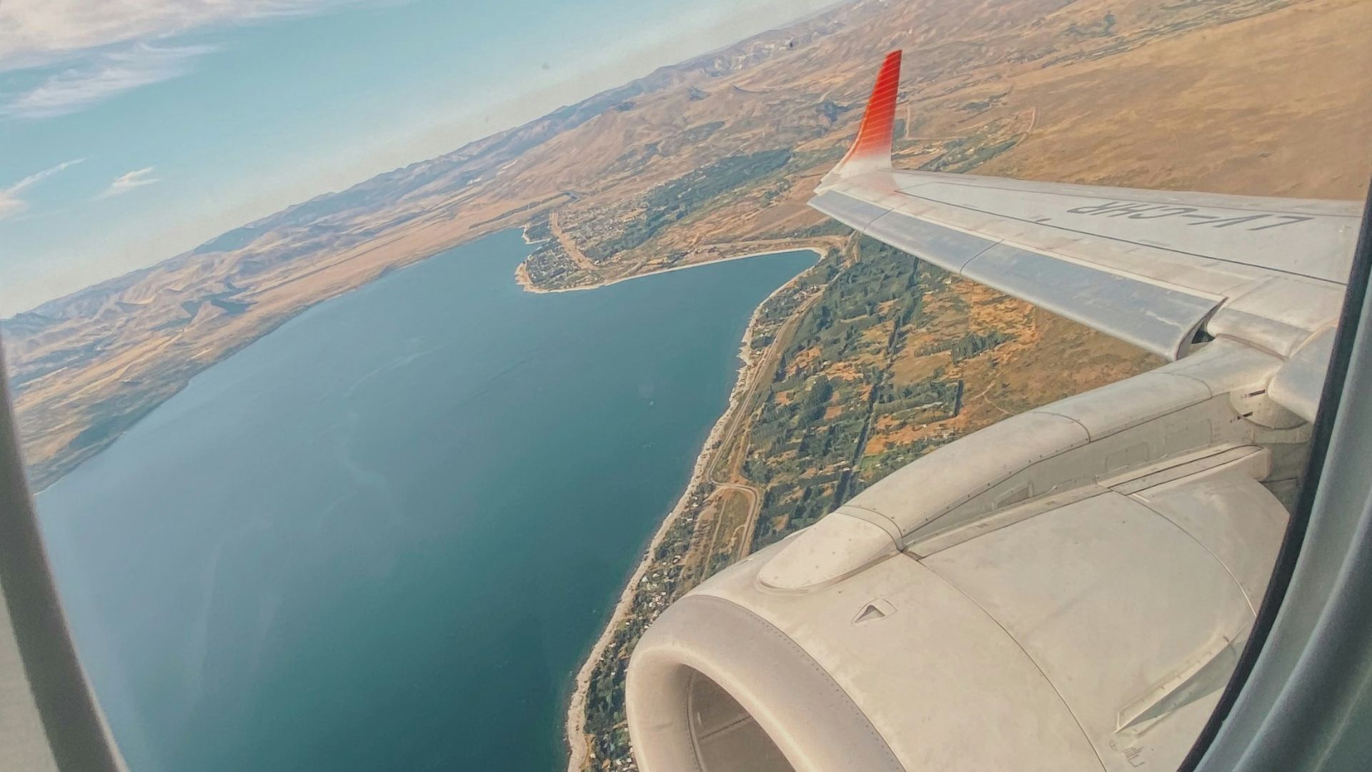 white and red airplane wing over the sea during daytime