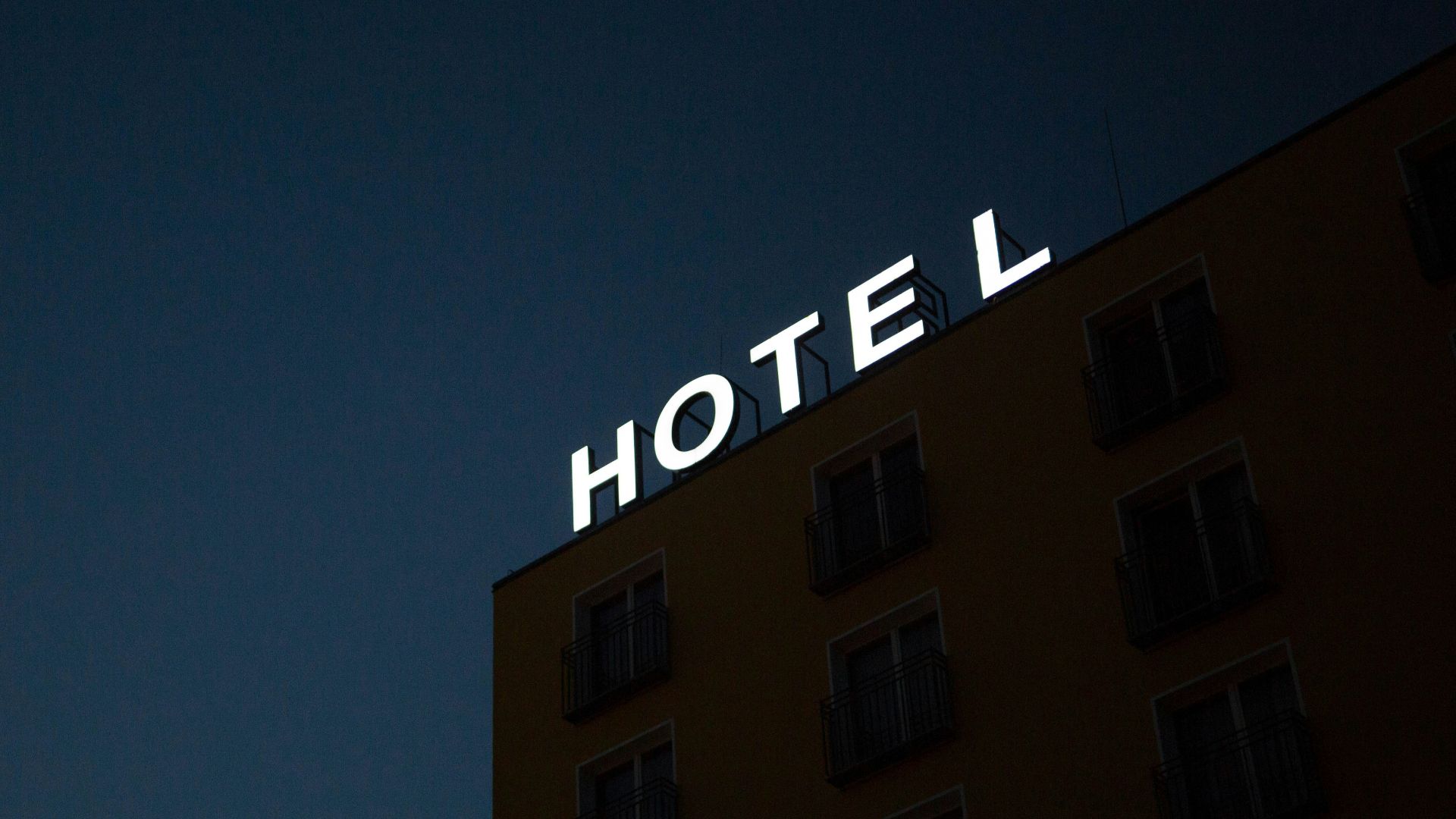 low-angle photo of Hotel lighted signage on top of brown building during nighttime