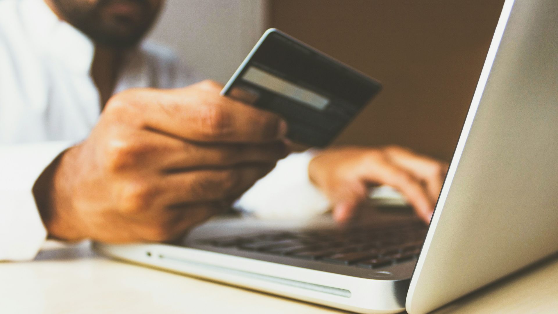 person using laptop computer holding card