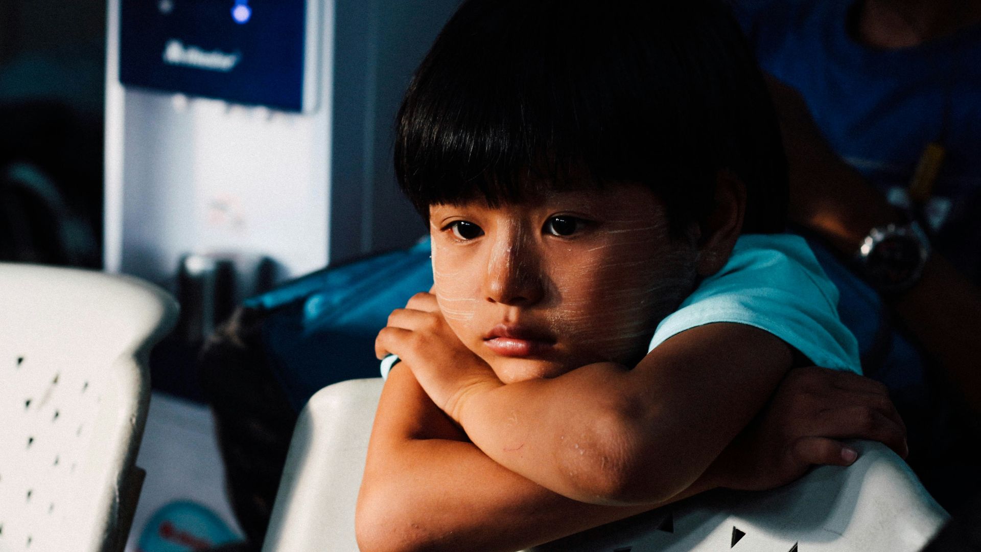 boy leaning on white chair