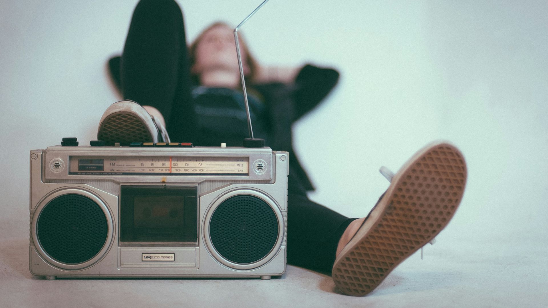 woman laying on bed near gray radio