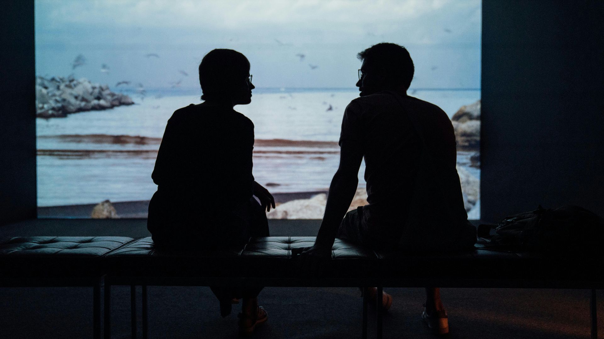 silhouette of man and woman sitting on ottoman