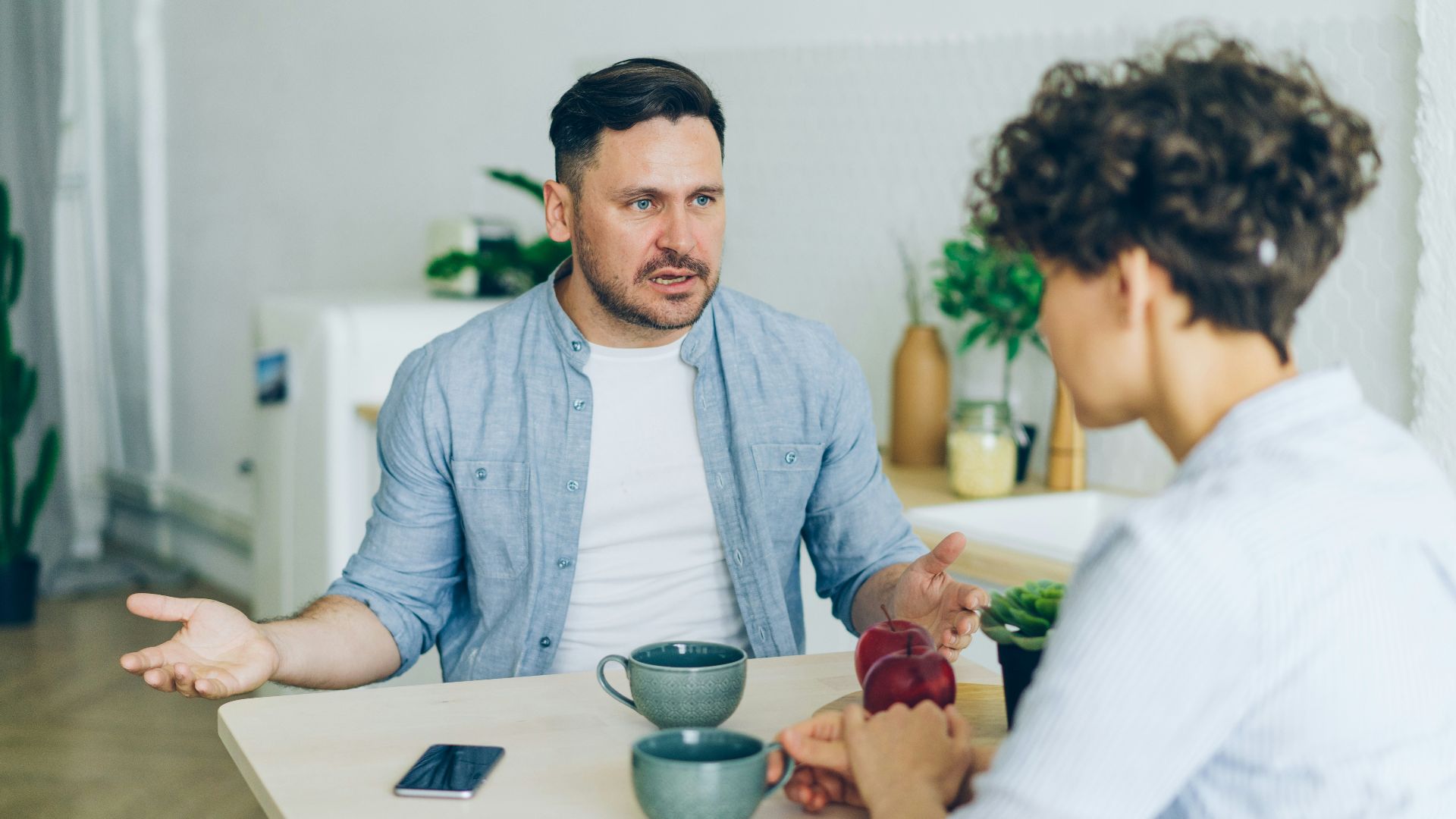 a man sitting at a table talking to a woman