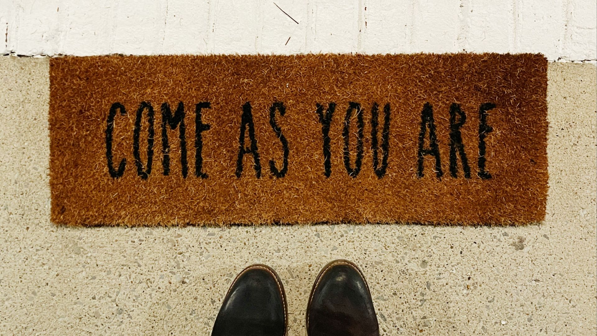 person standing on brown and black welcome printed floor mat