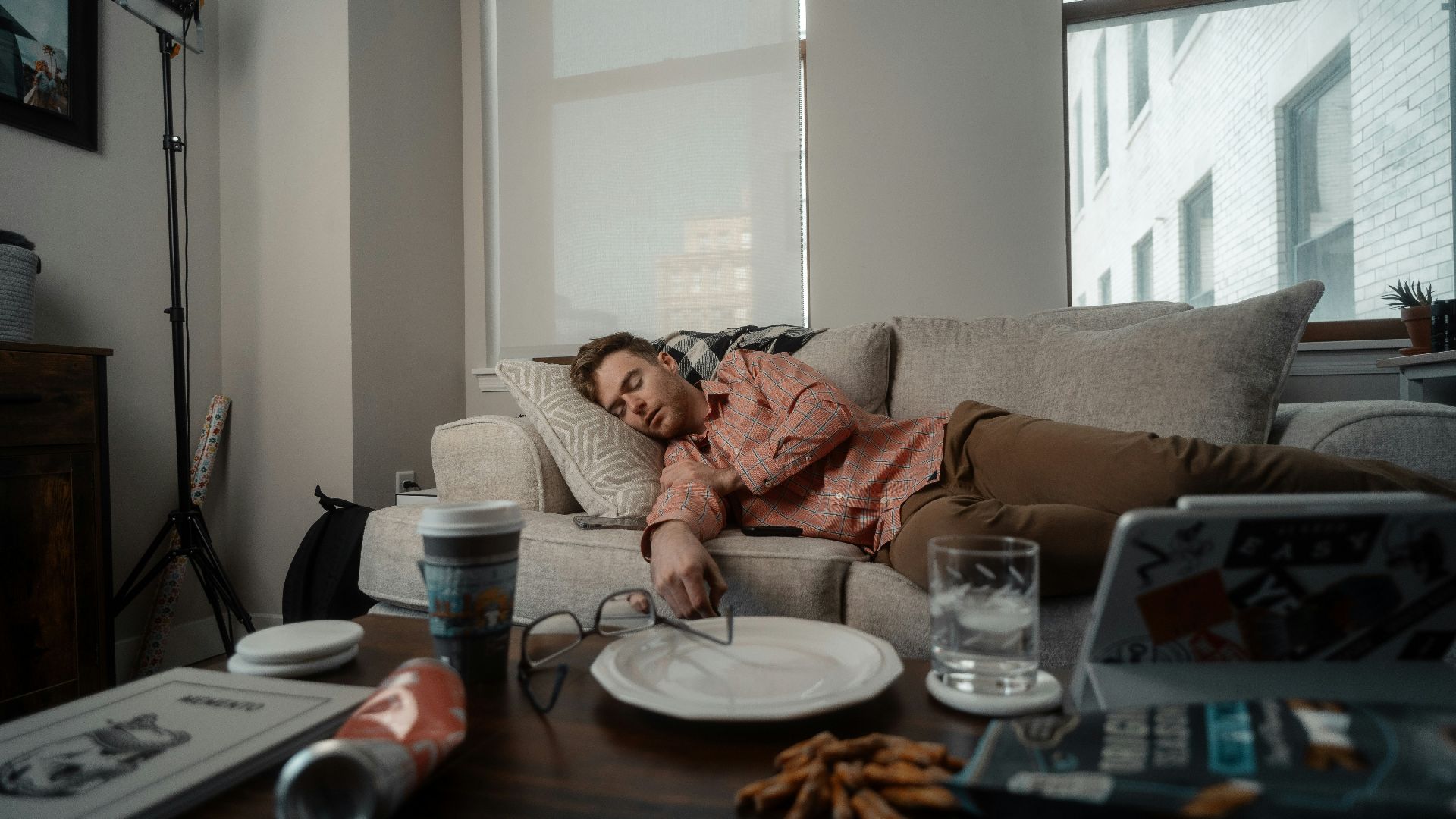 a woman laying on a couch with a plate of food