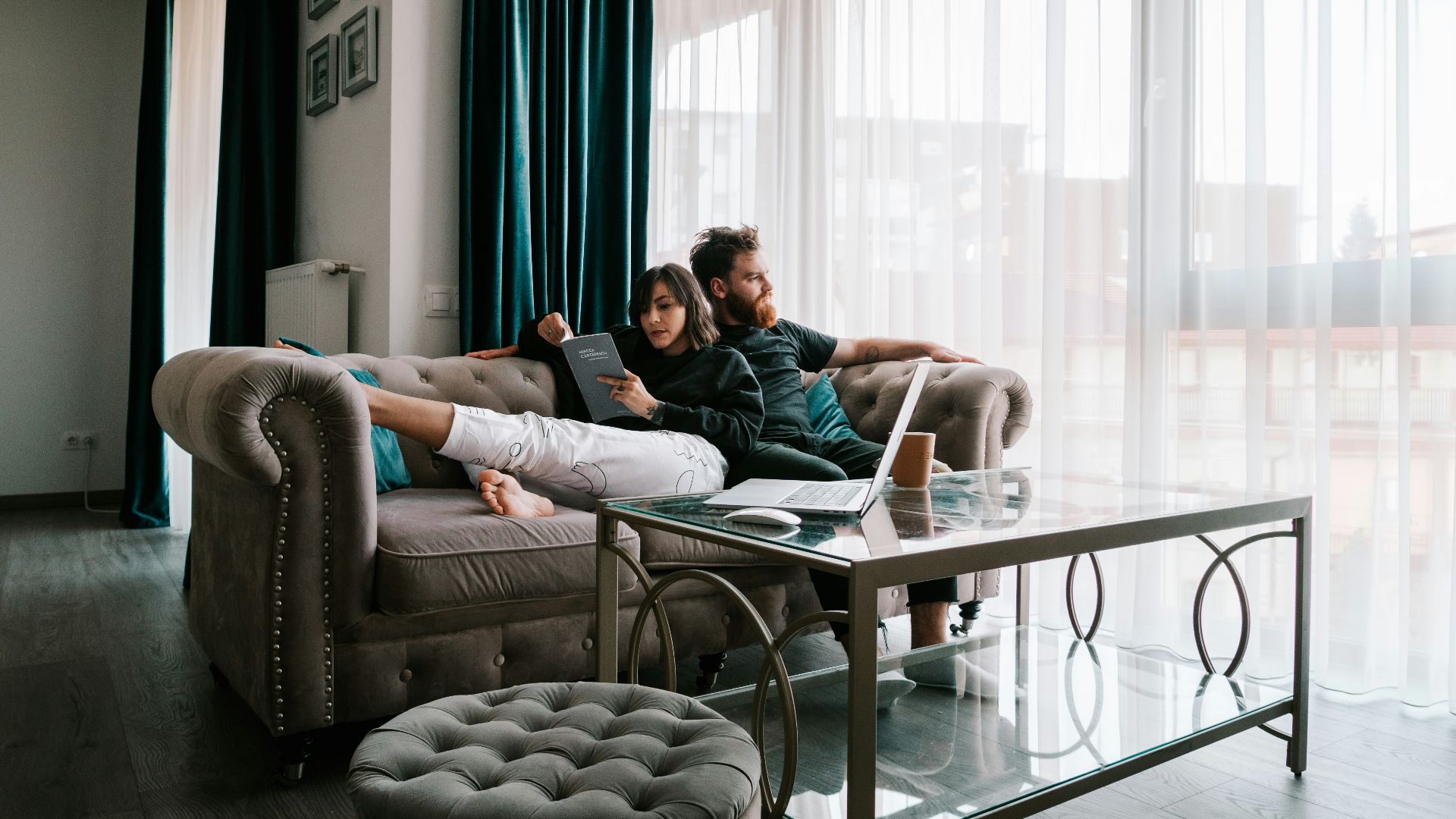 2 women sitting on sofa near window