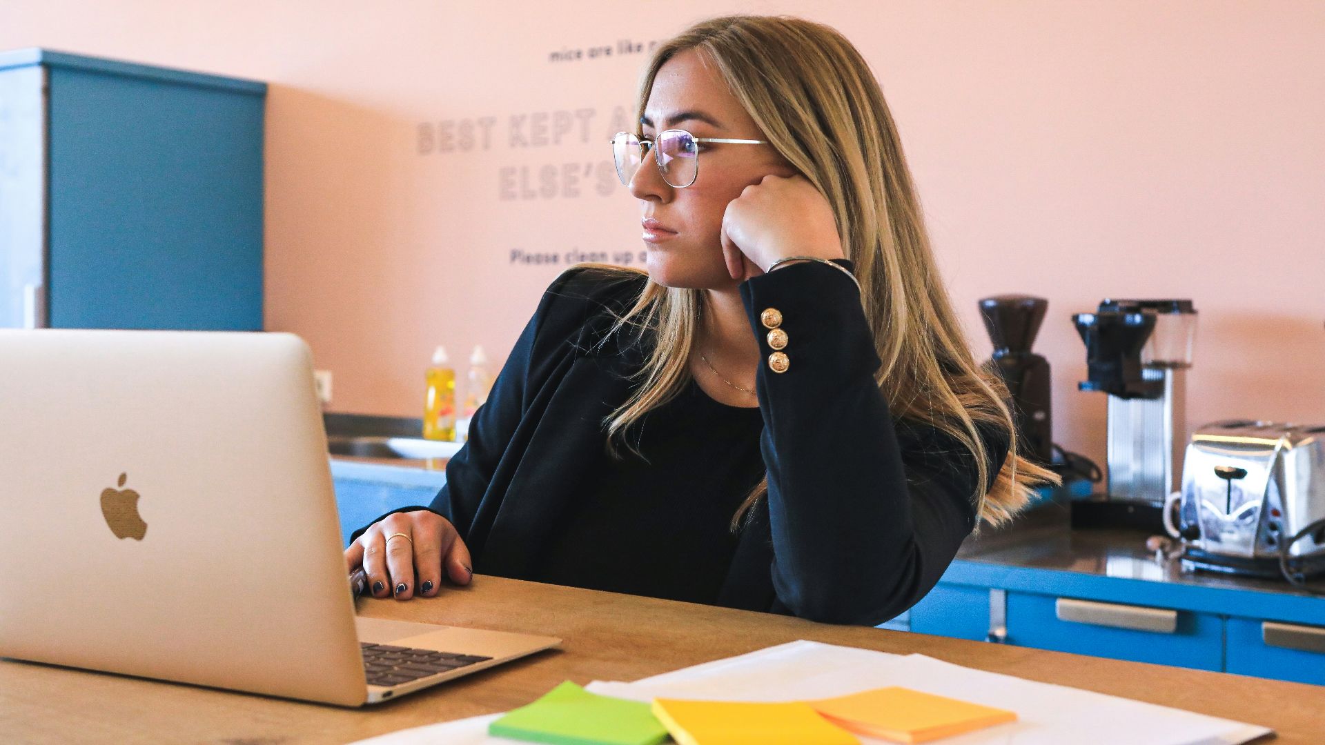 woman in black long sleeve shirt wearing black framed eyeglasses using macbook