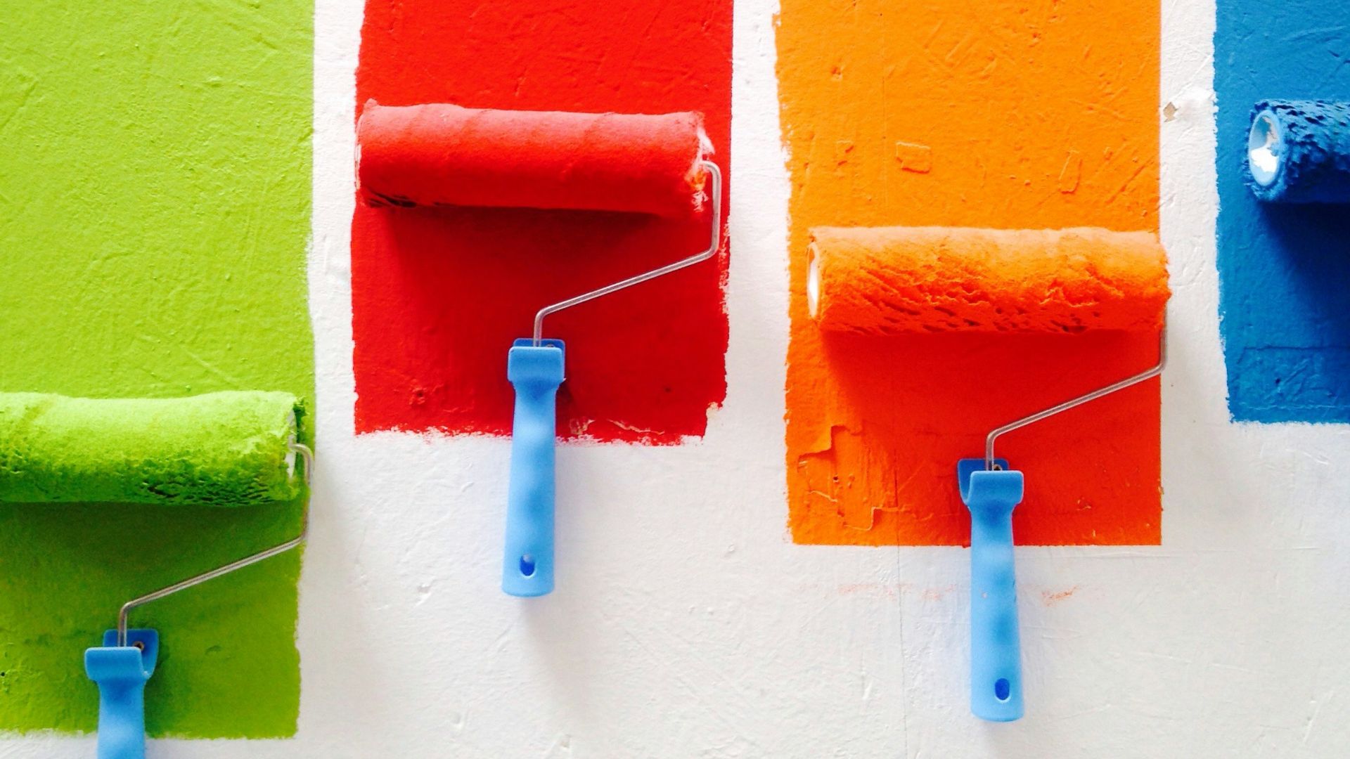 four orange, green, blue, and red paint rollers
