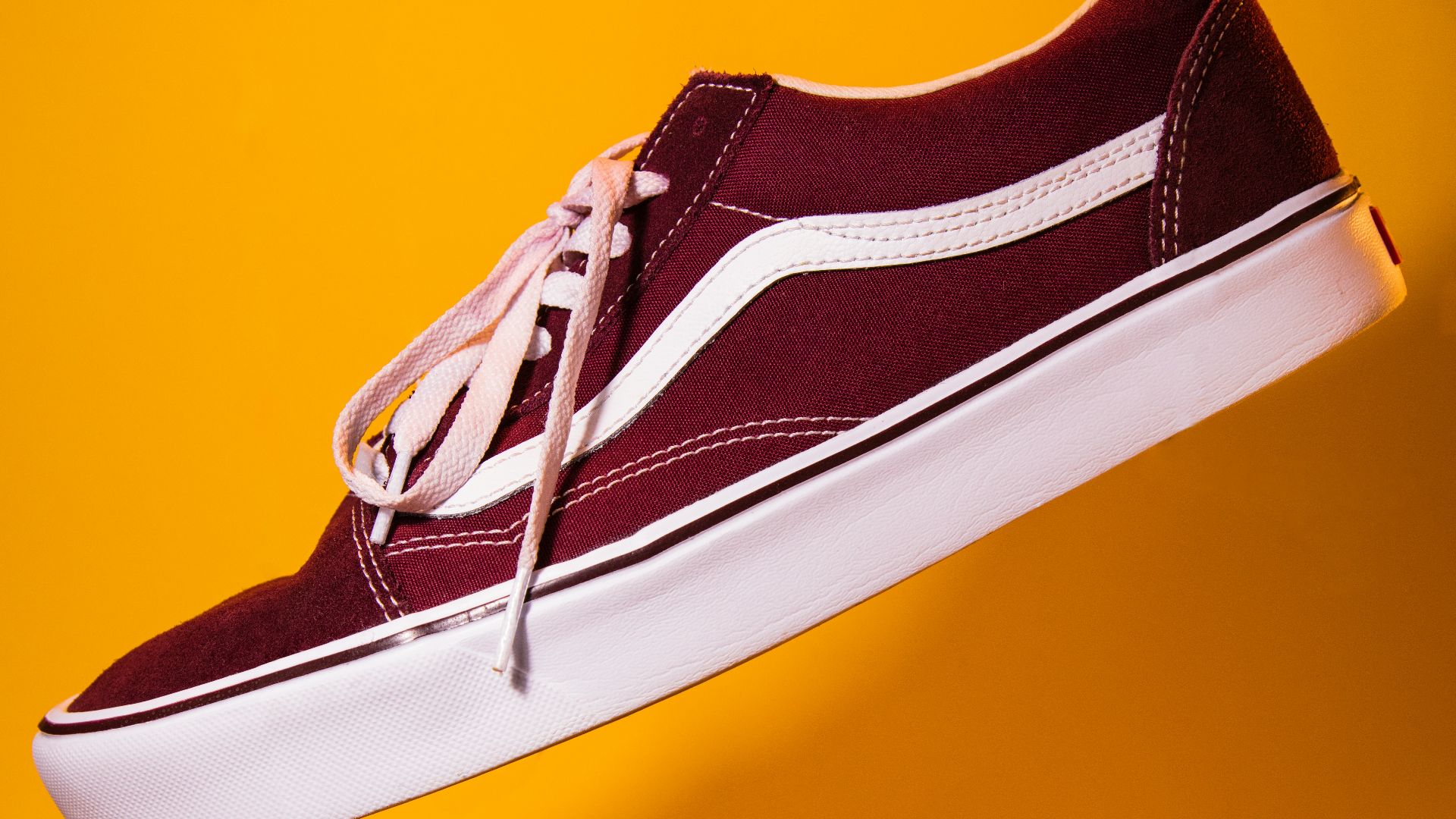 unpaired maroon plimsoll on top of yellow textile