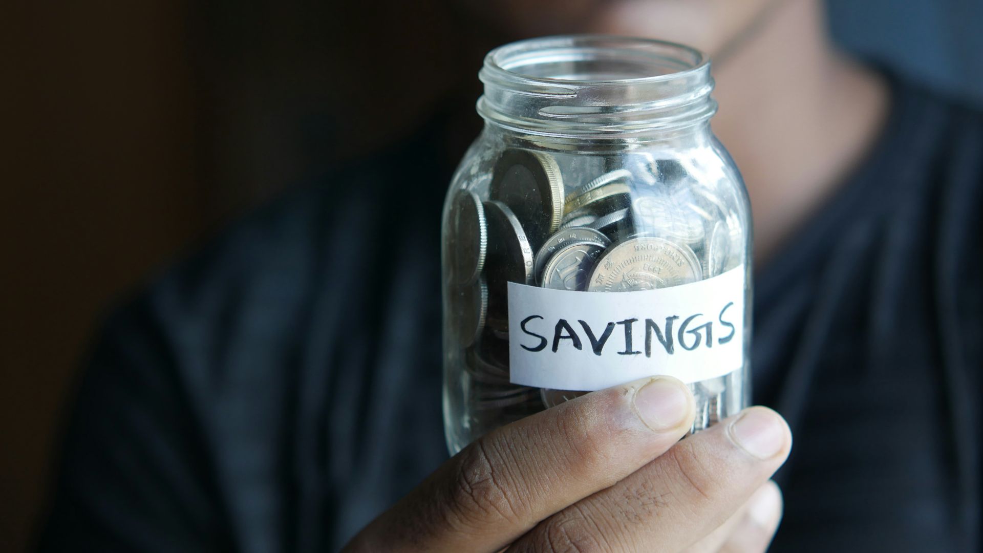 a man holding a jar with a savings label on it