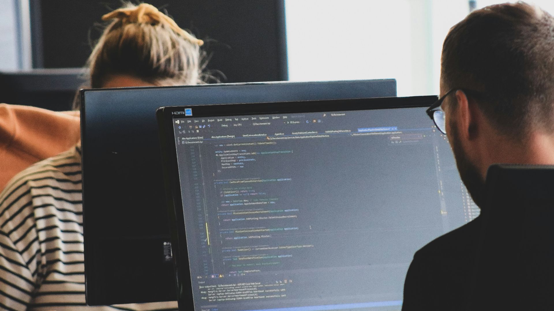 woman in black shirt sitting beside black flat screen computer monitor