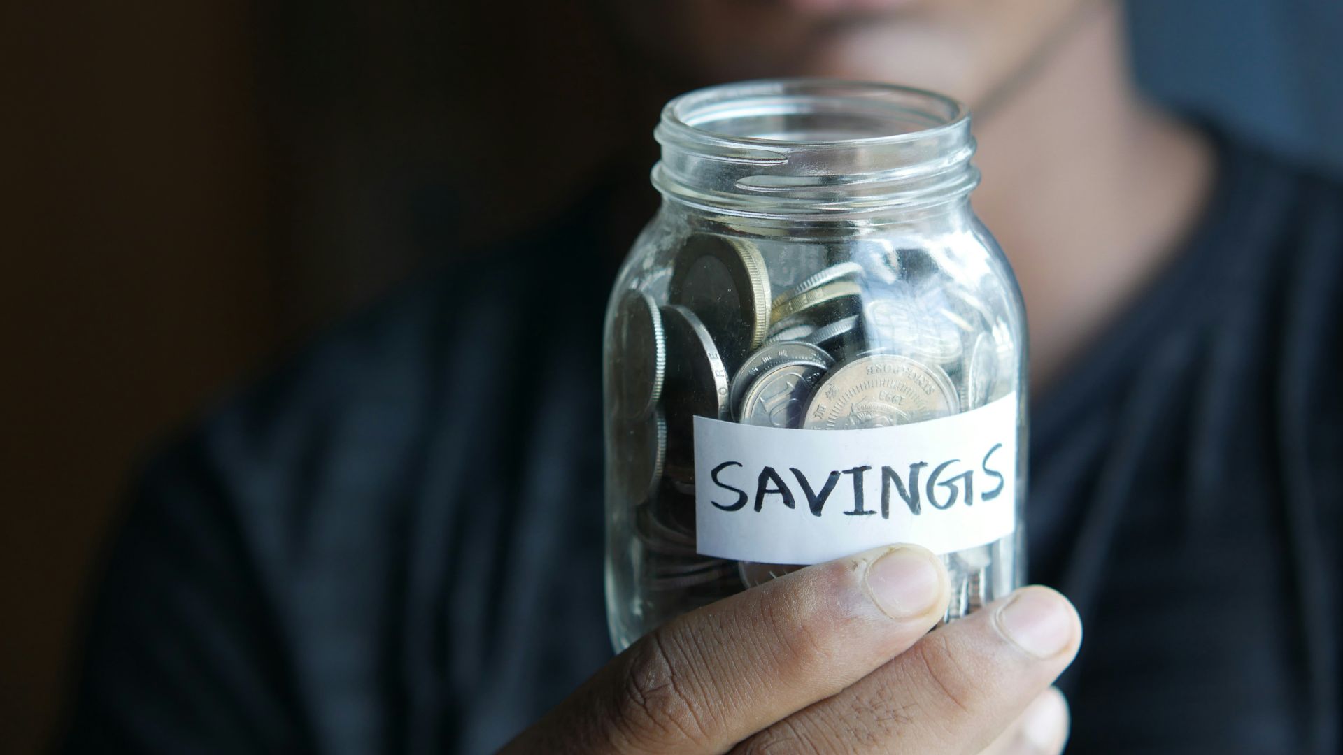 a man holding a jar with a savings label on it
