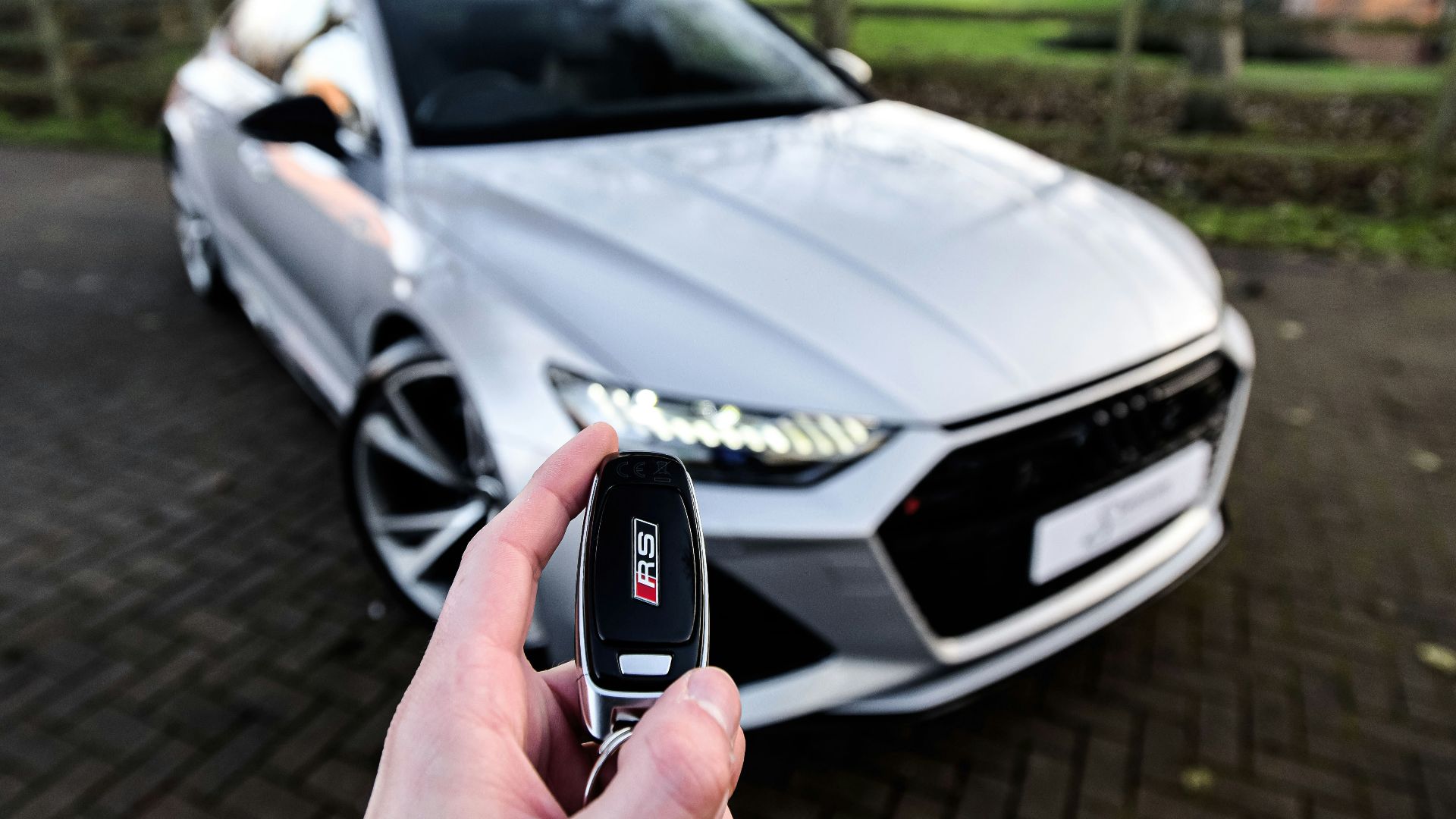 a person holding a car key in front of a silver car