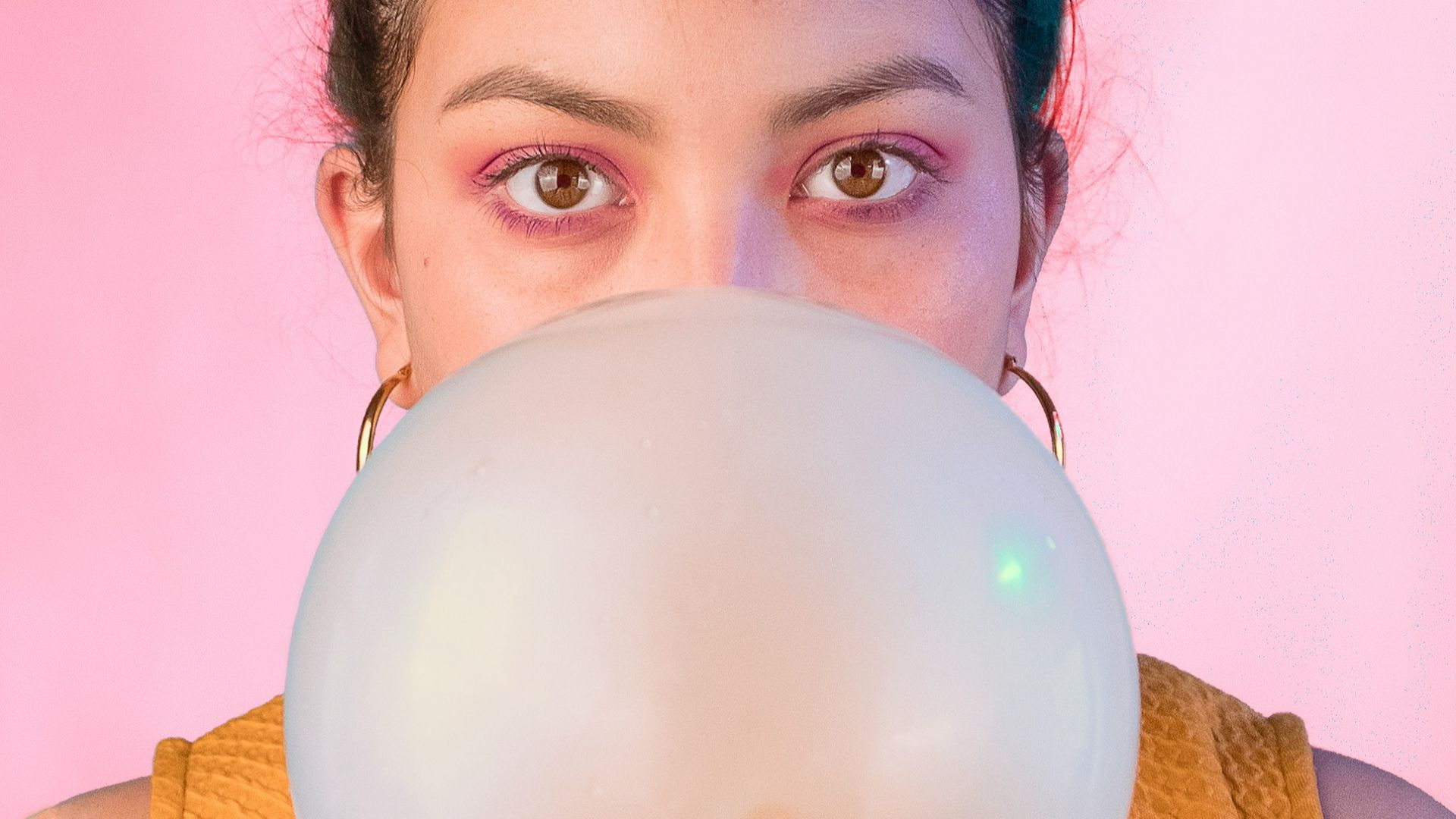 woman in yellow sleeveless shirt blowing gum