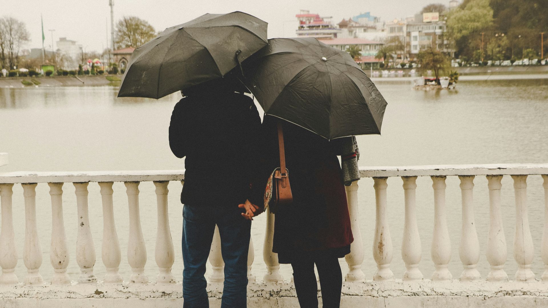 man and woman holding black umbrellas