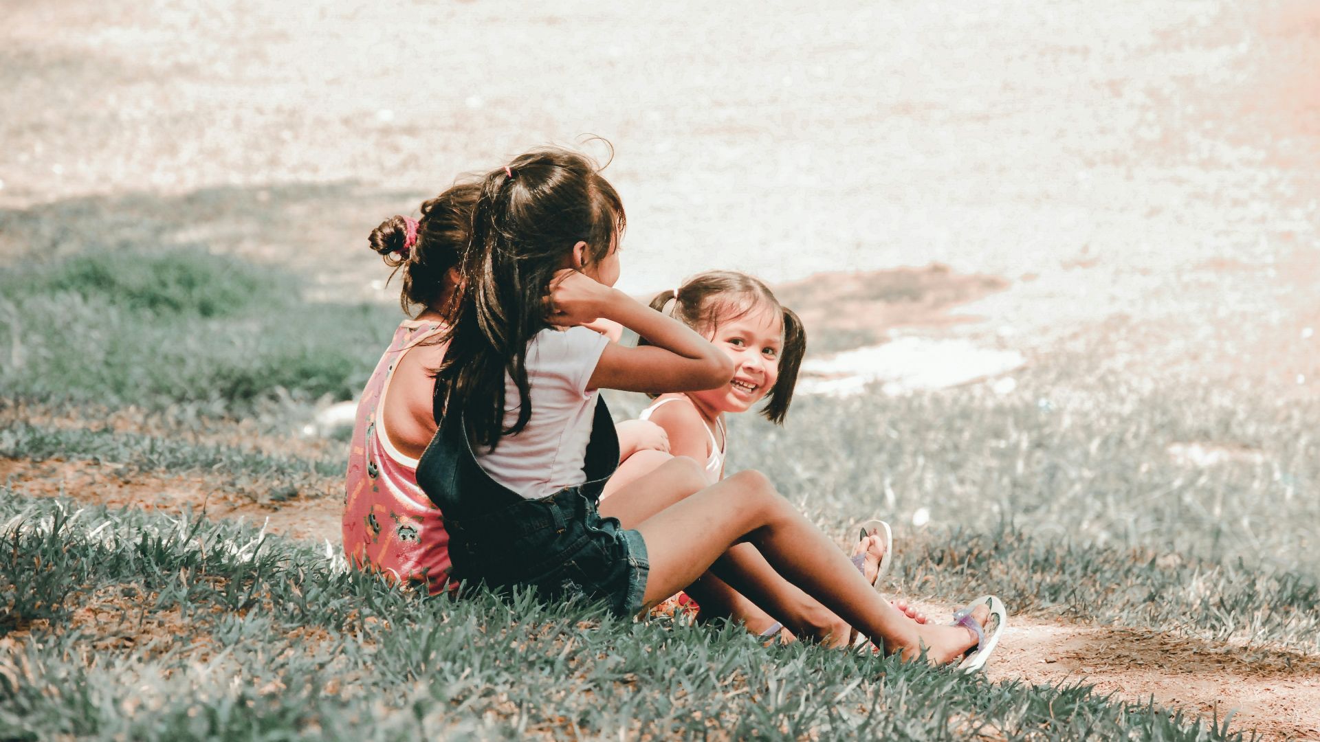 three children sitting on grass