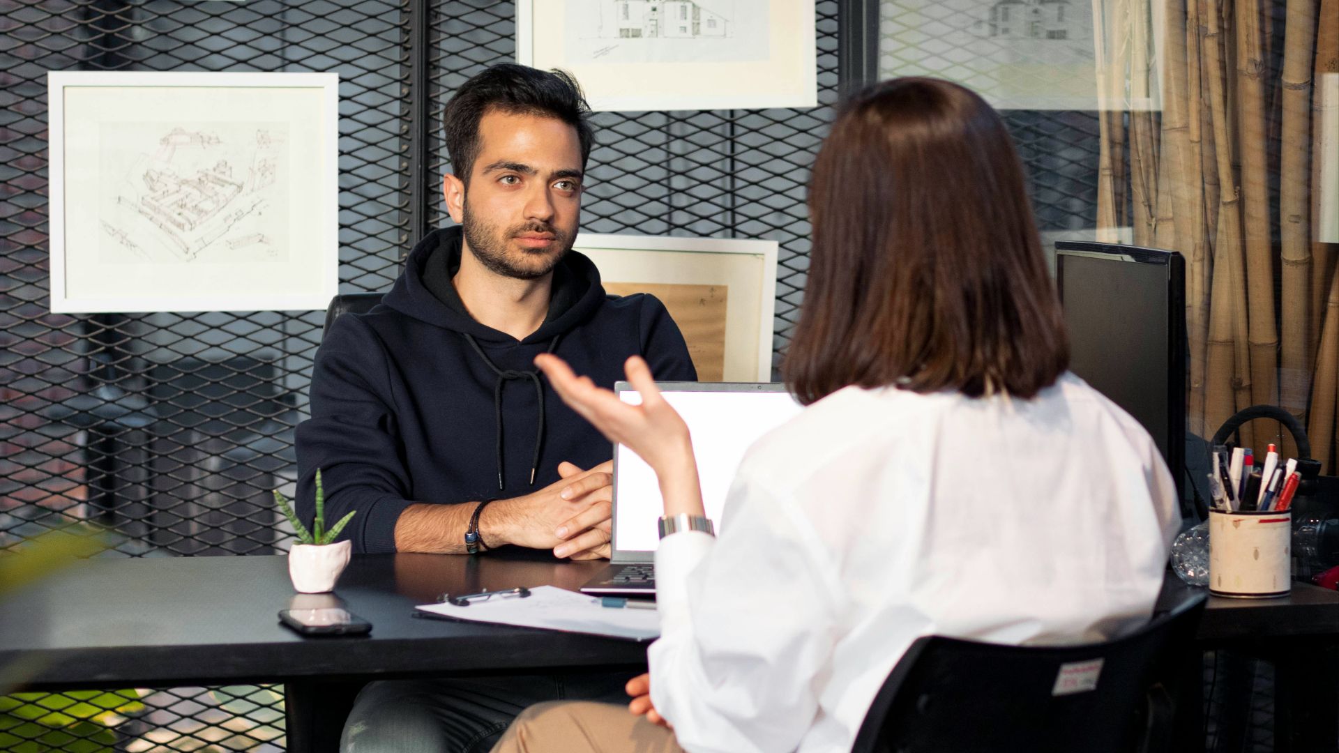 a man sitting at a desk talking to a woman