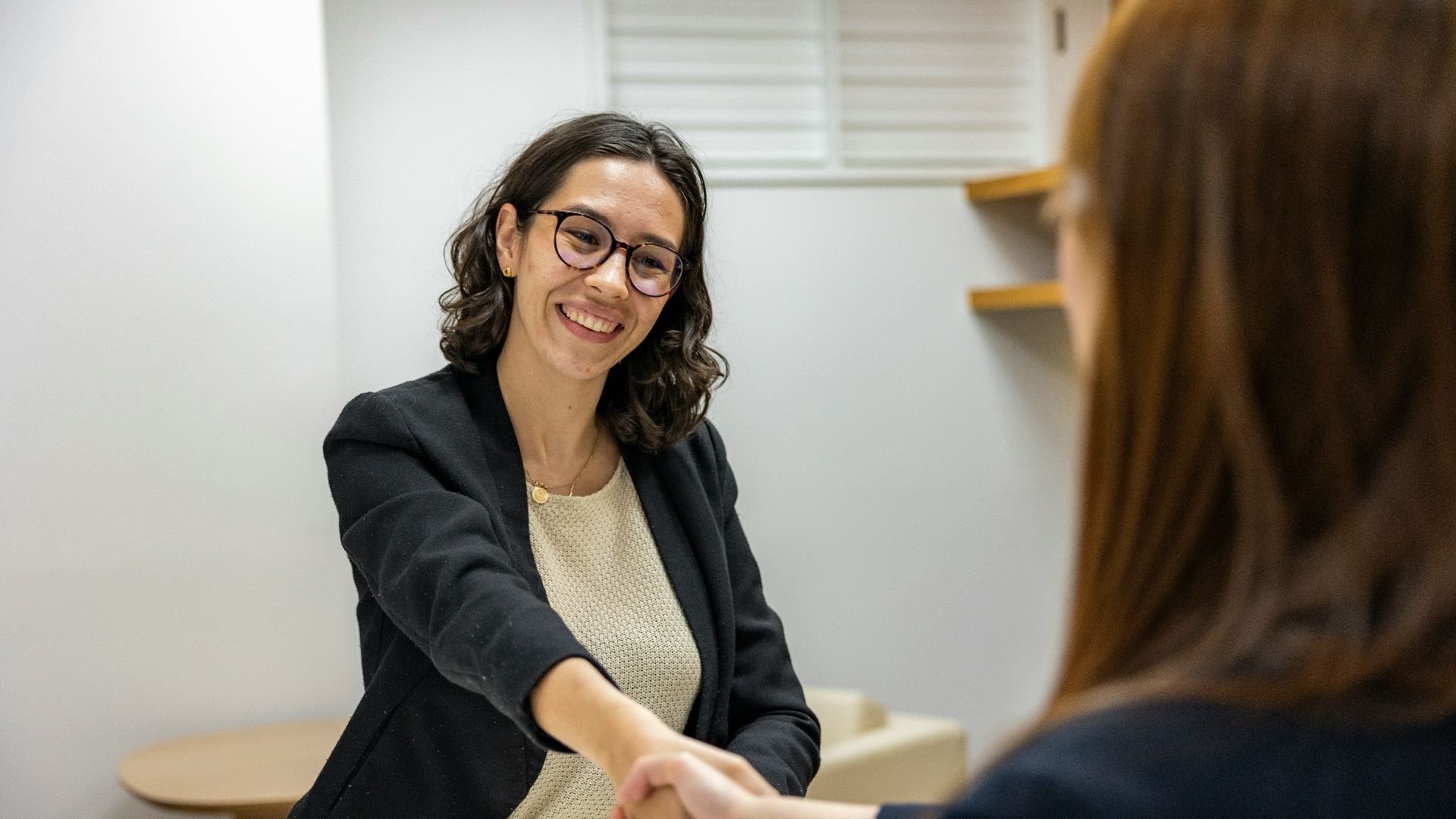 a woman shaking hands with another woman sitting at a table