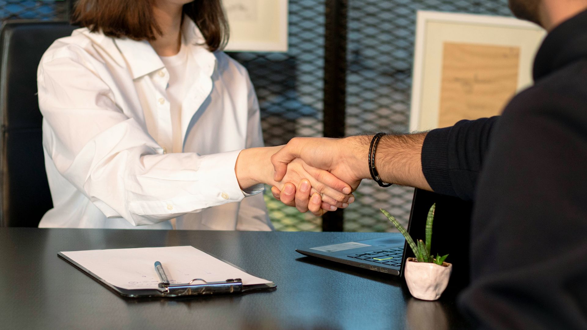 a man and a woman shaking hands in front of a laptop