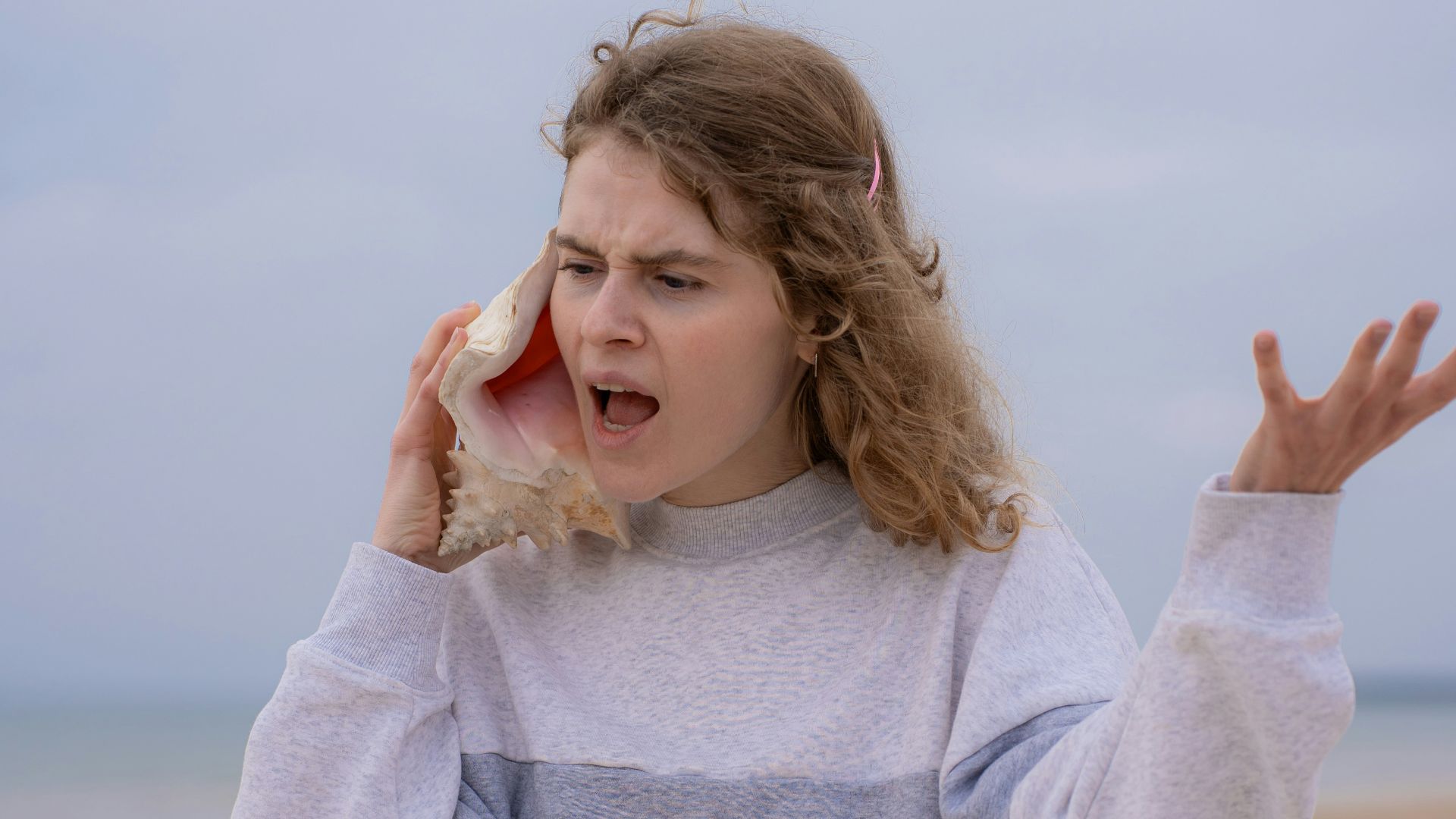 a woman on the beach holding a cell phone to her ear