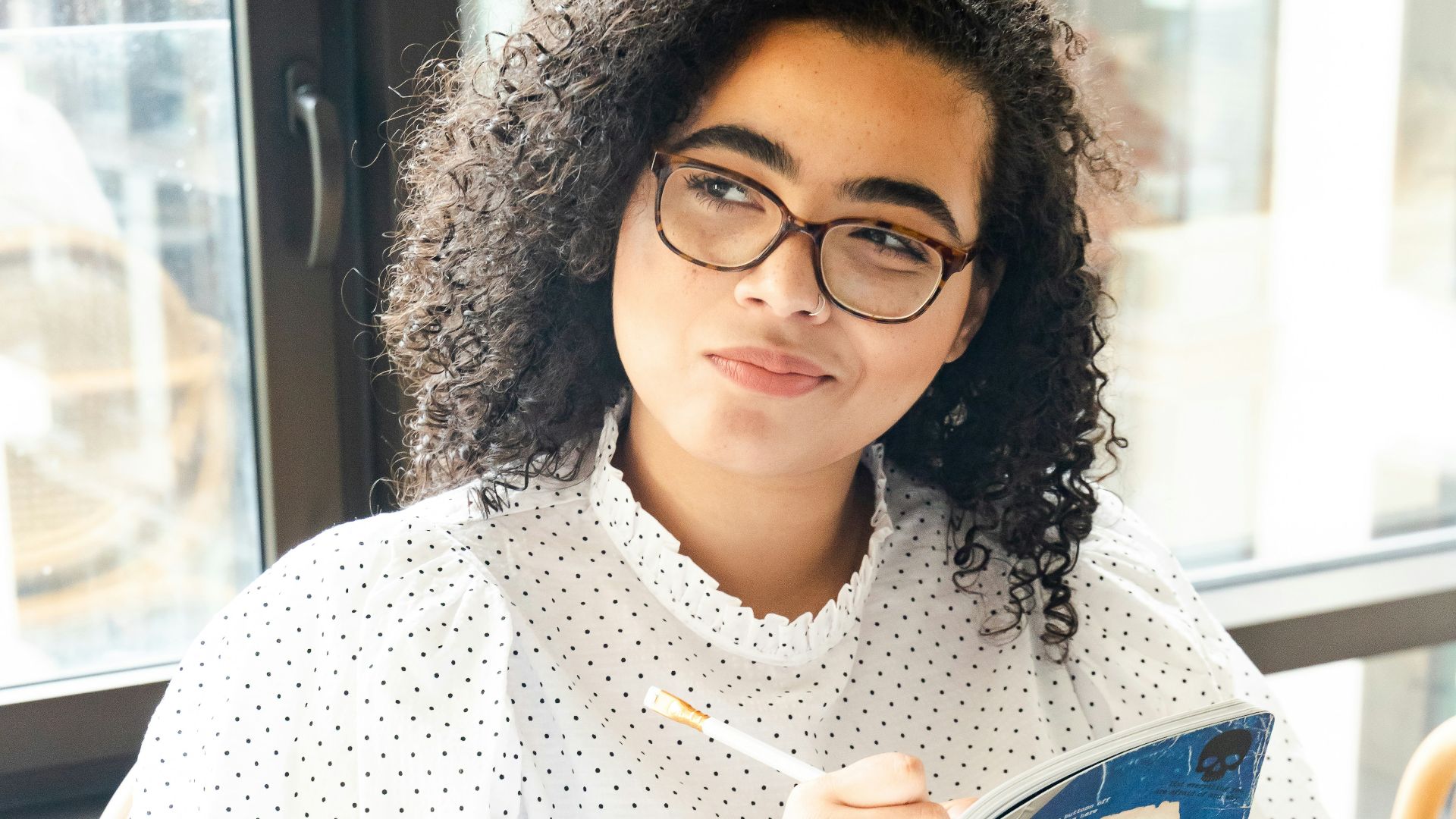 woman in white and black polka dot shirt holding blue and white book