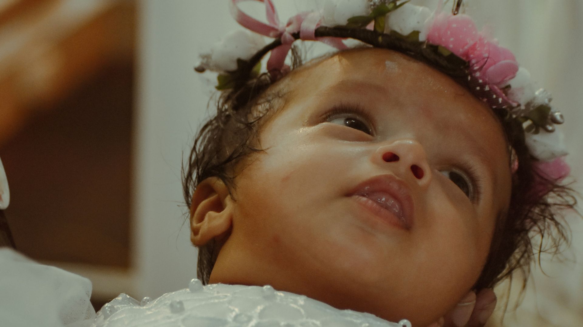 a little girl in a white dress with a flower in her hair