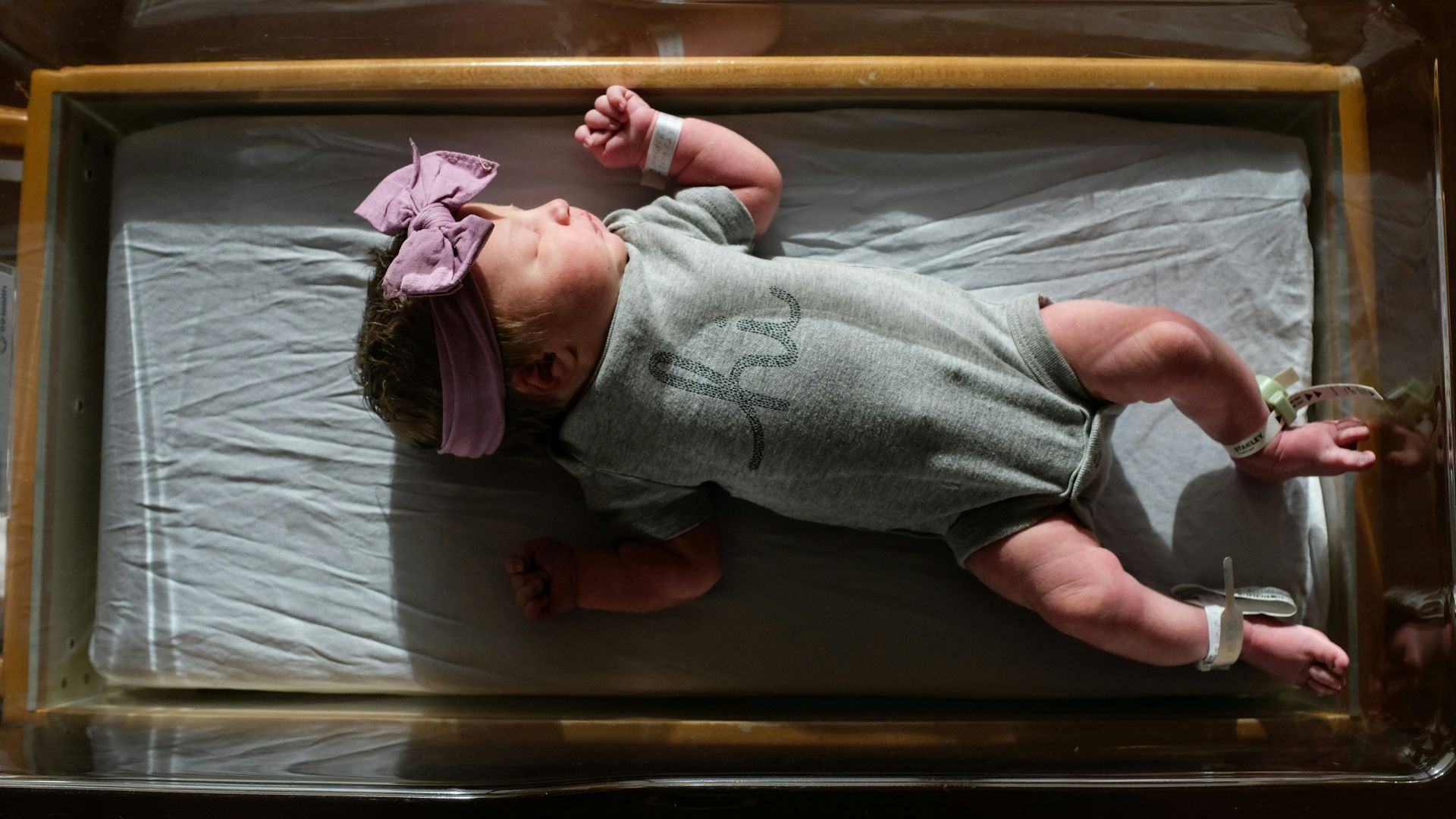 a baby laying on a bed with a pink headband