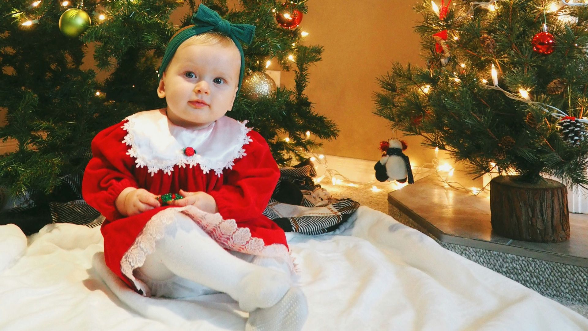 girl in red and white santa costume standing beside green christmas tree